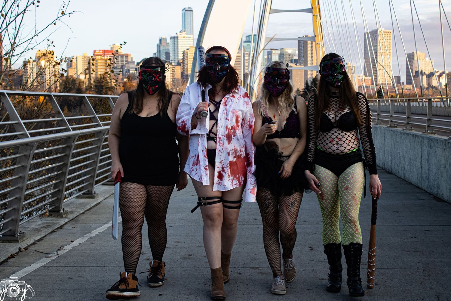 Group walking along urban bridge walkway at dusk with city skyline in background.