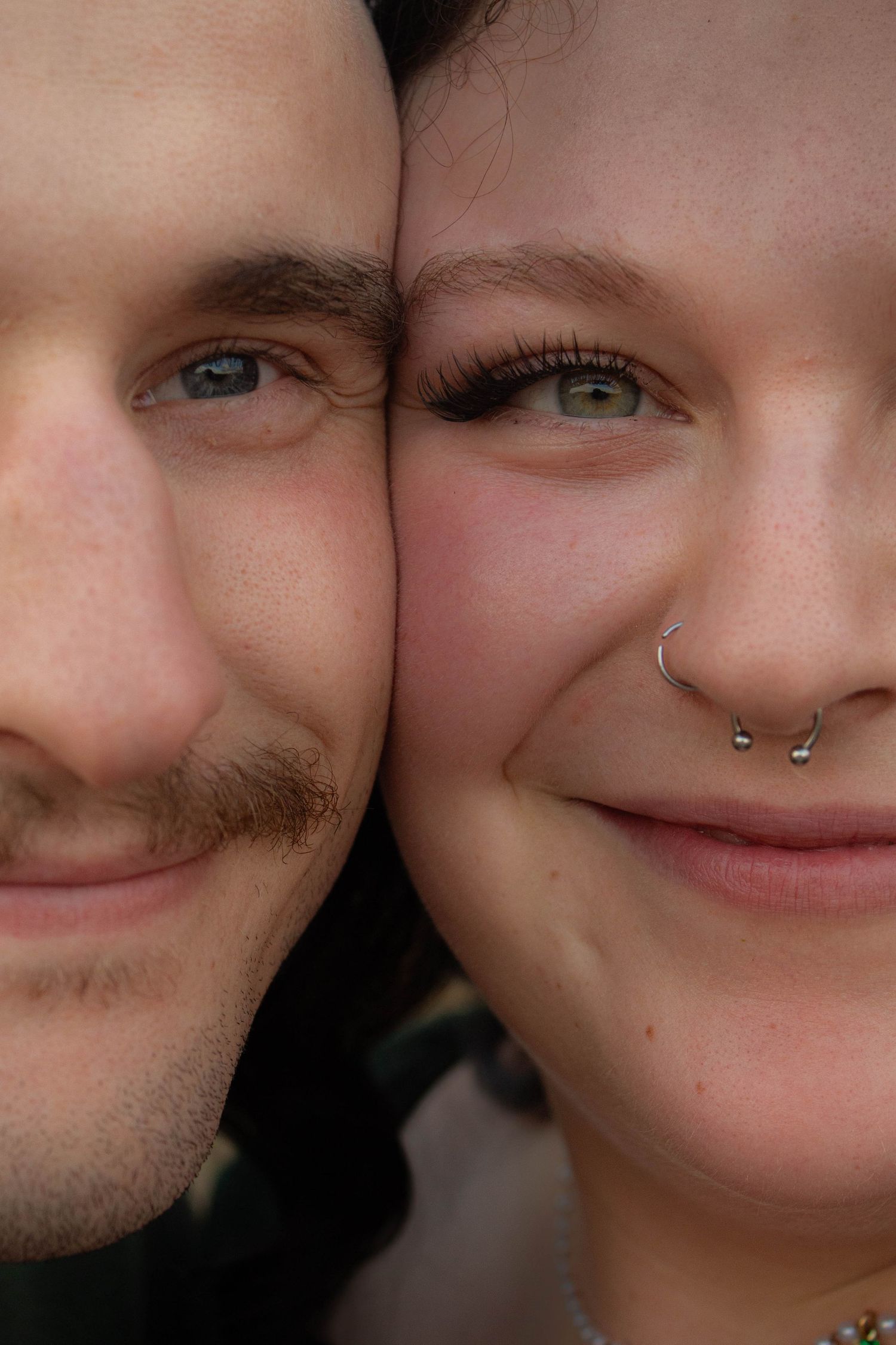 An intimate close-up portrait showcasing facial features and a nose piercing.