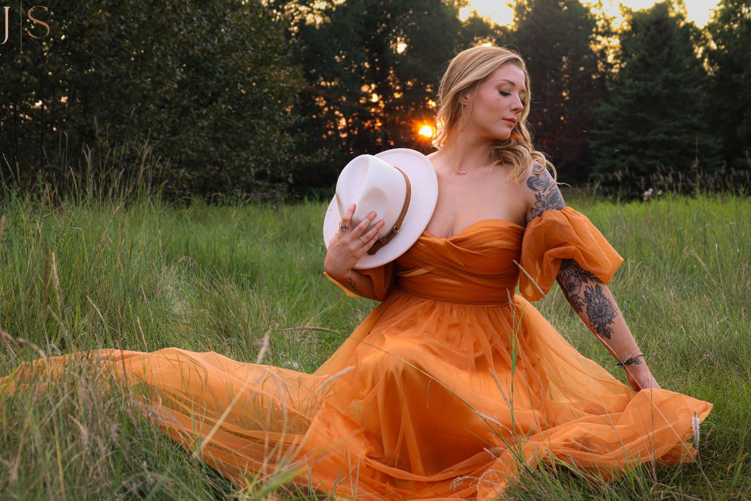 A flowing orange dress twirls gracefully in a sunlit meadow during golden hour.