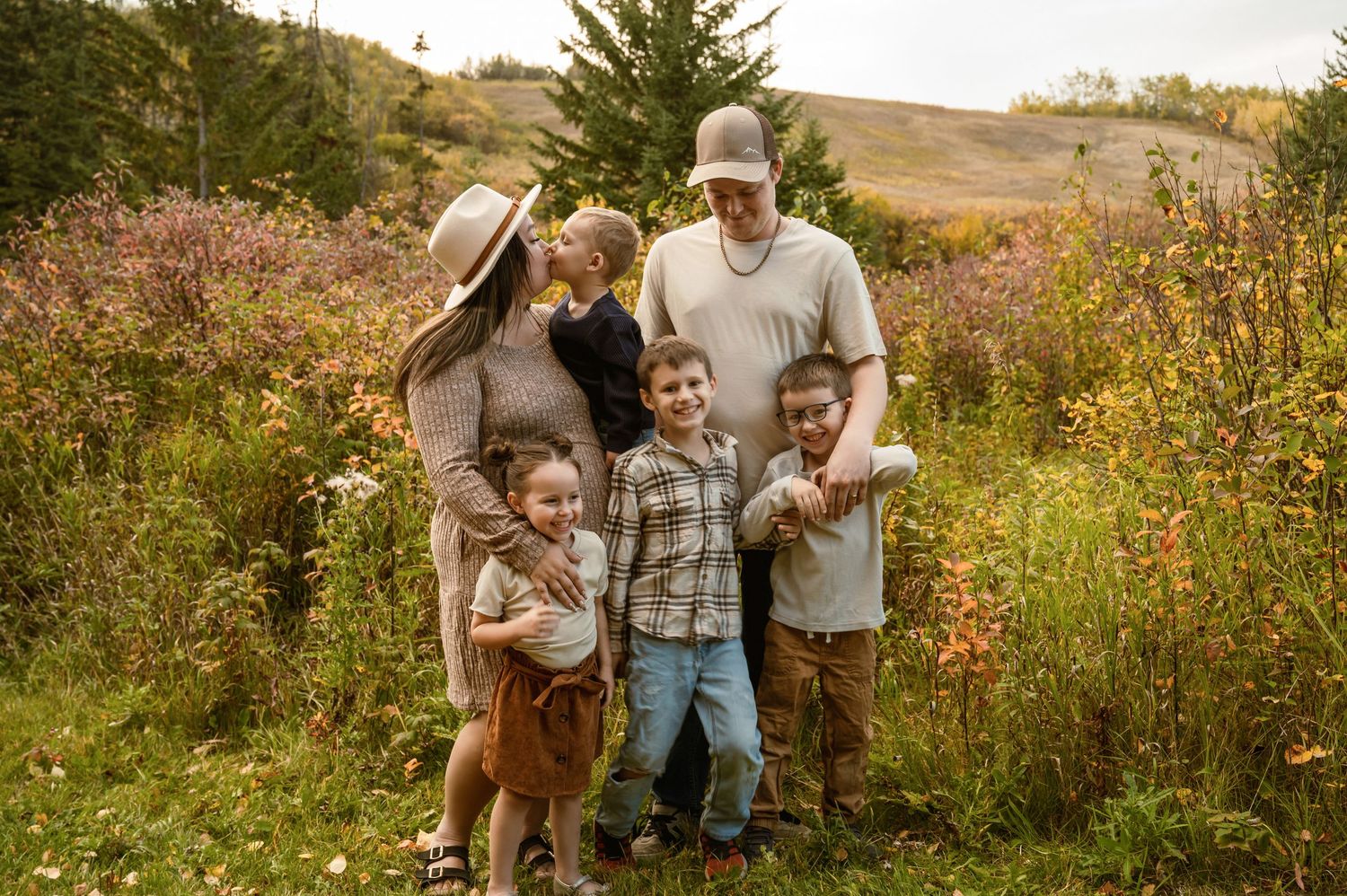 Family enjoys autumn afternoon together in field of wildflowers during golden hour sunset.