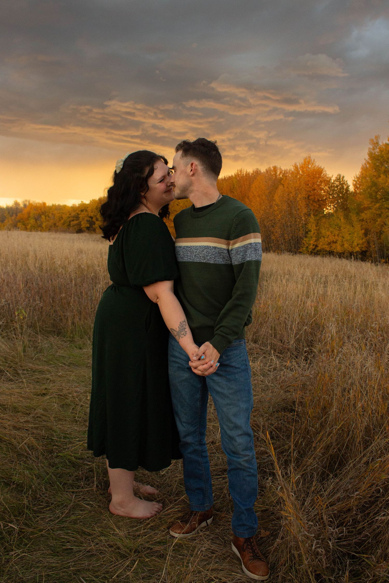 A romantic sunset moment in a golden field with autumn trees in the background.