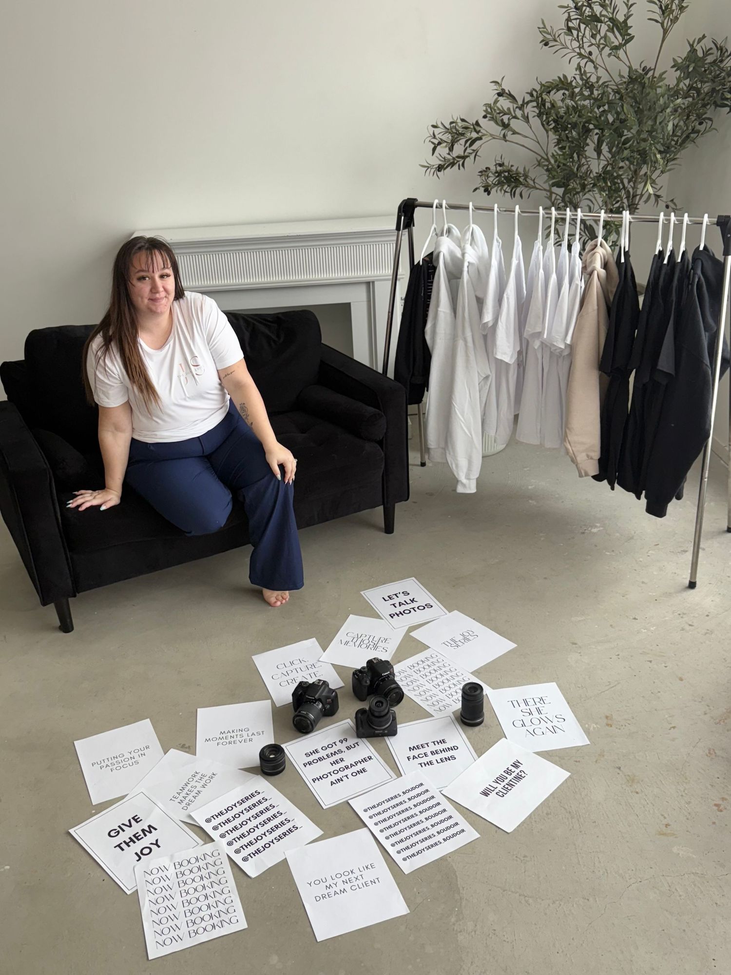 Interior scene showing papers scattered on floor near a couch with clothing rack displaying black and white garments.