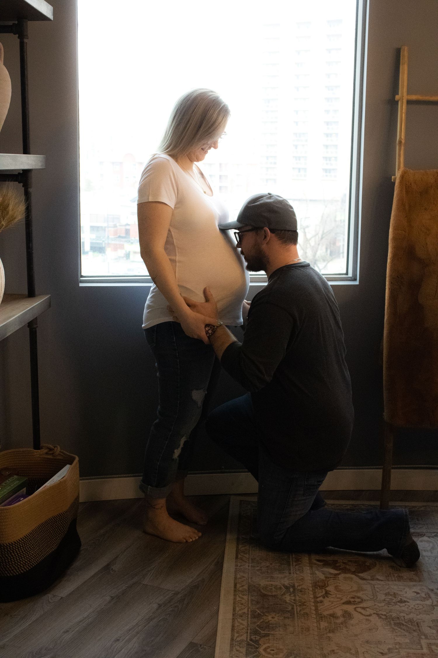 An intimate maternity moment captured by a window in a home setting.