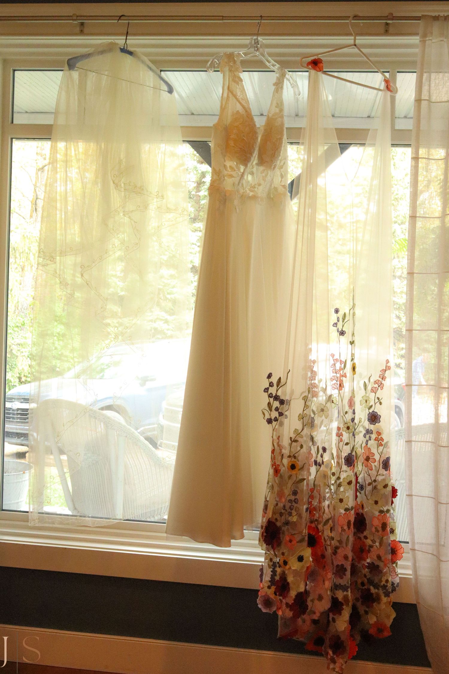 A series of sheer curtains with floral patterns along the bottom edge hanging in front of windows in a room.