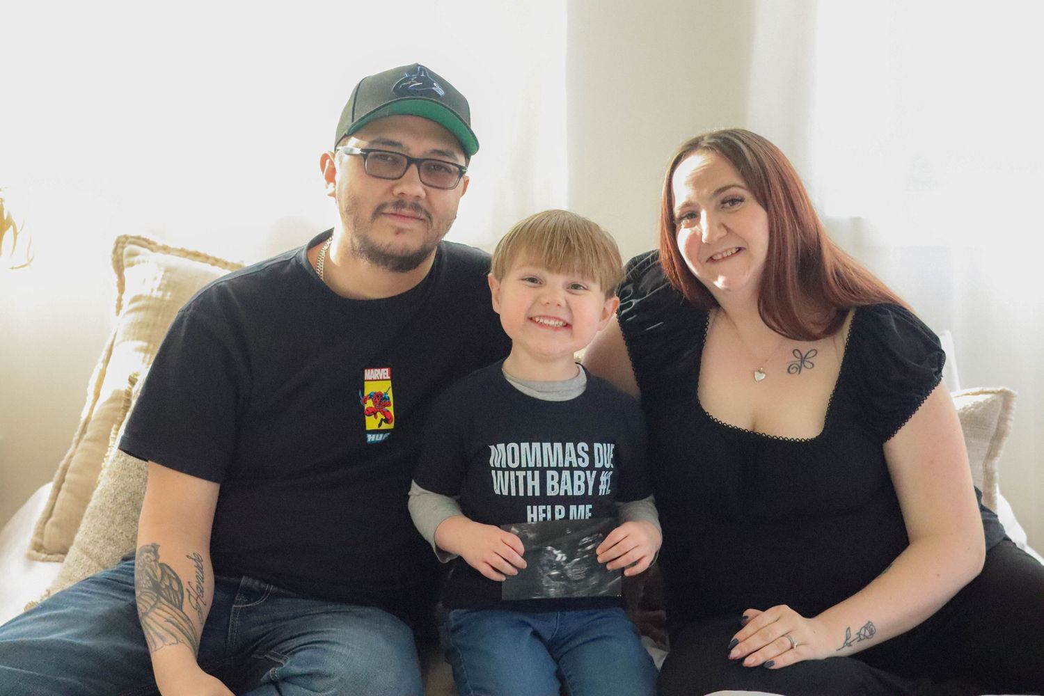 Family photo on a cream couch with sports-themed pregnancy announcement.