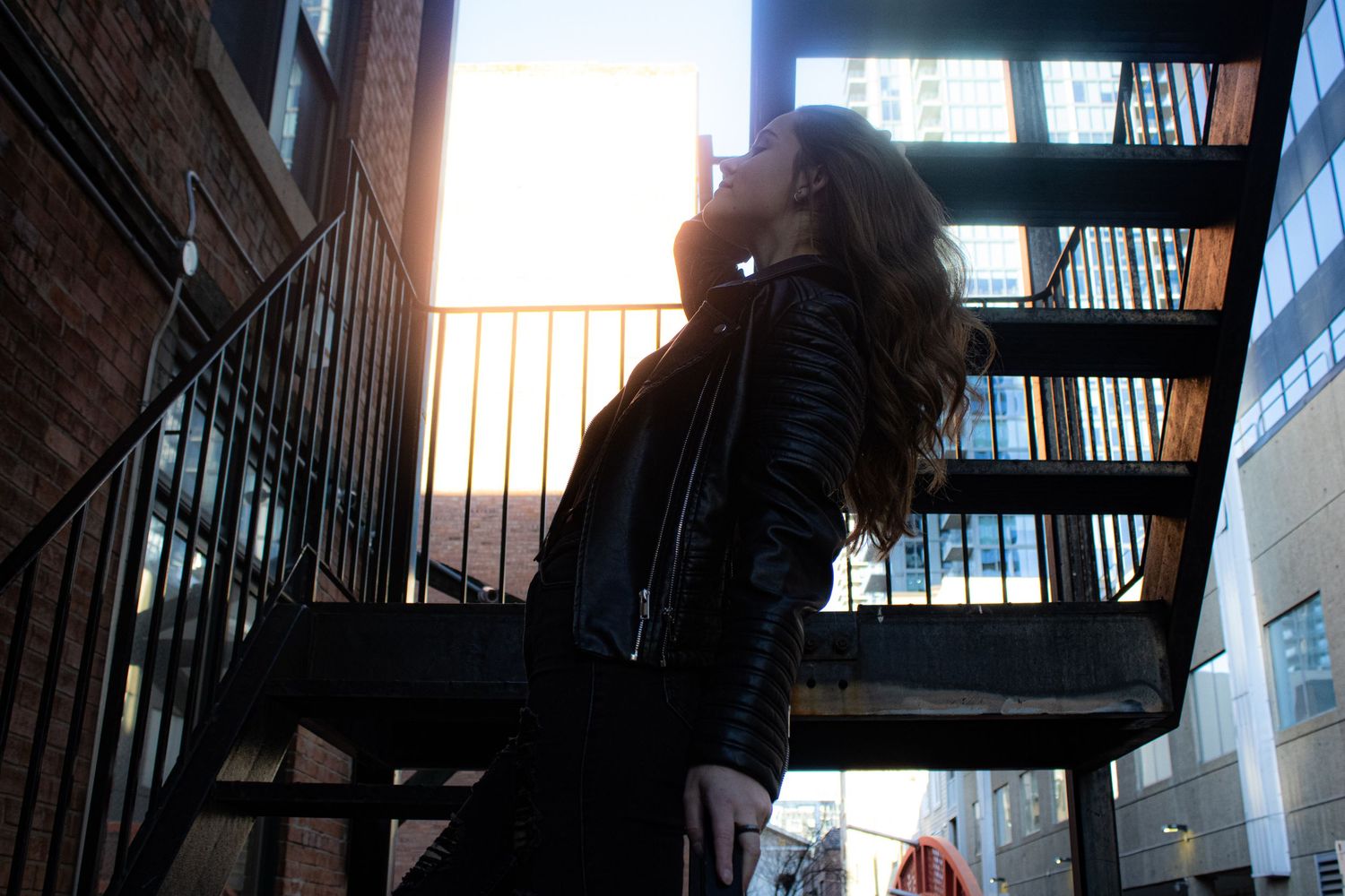 Silhouette shot on metal fire escape stairs during sunset with dramatic lighting.