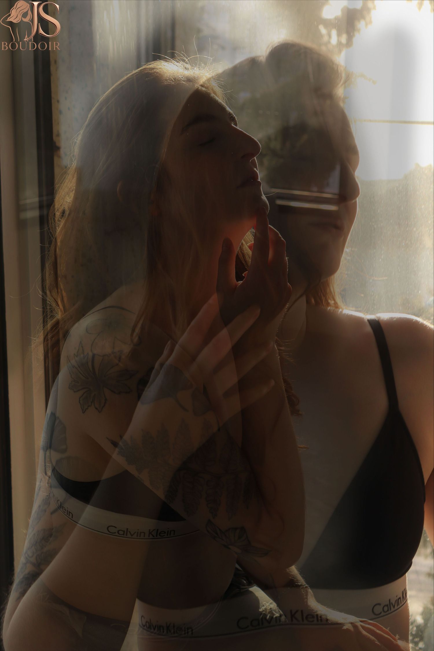 Artistic boudoir photograph with soft lighting and reflections creating a dreamy atmospheric mood.