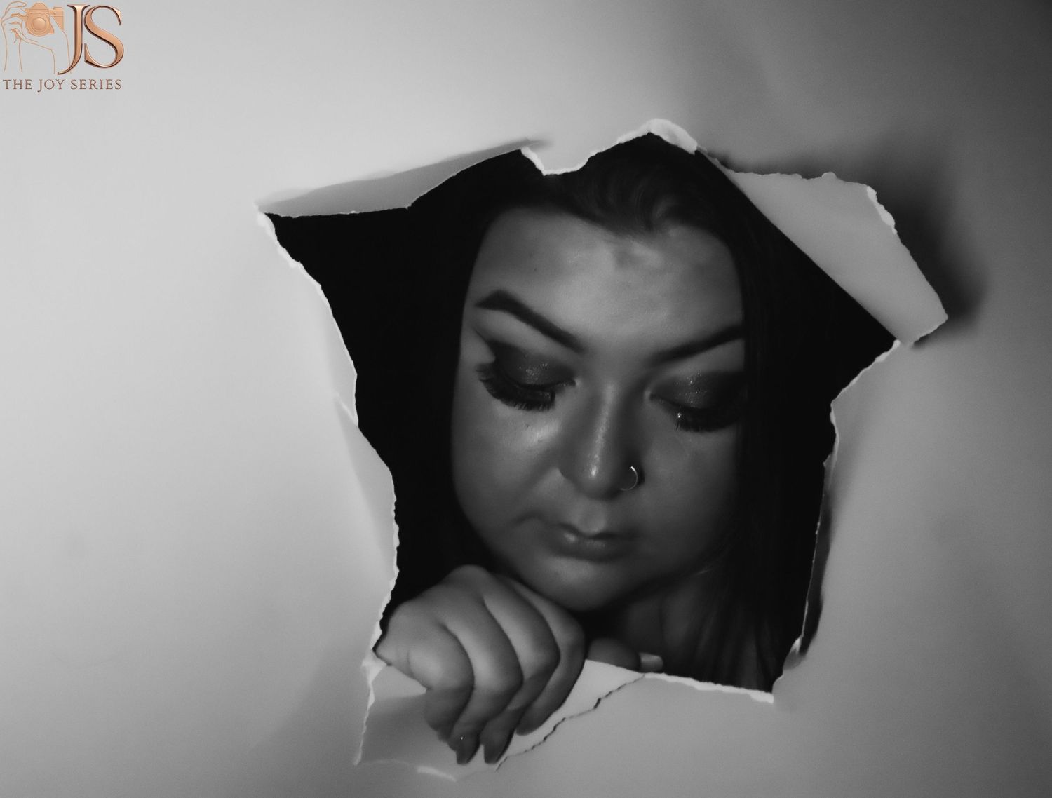 Black and white artistic portraits shot through torn paper creating a dramatic framed effect.
