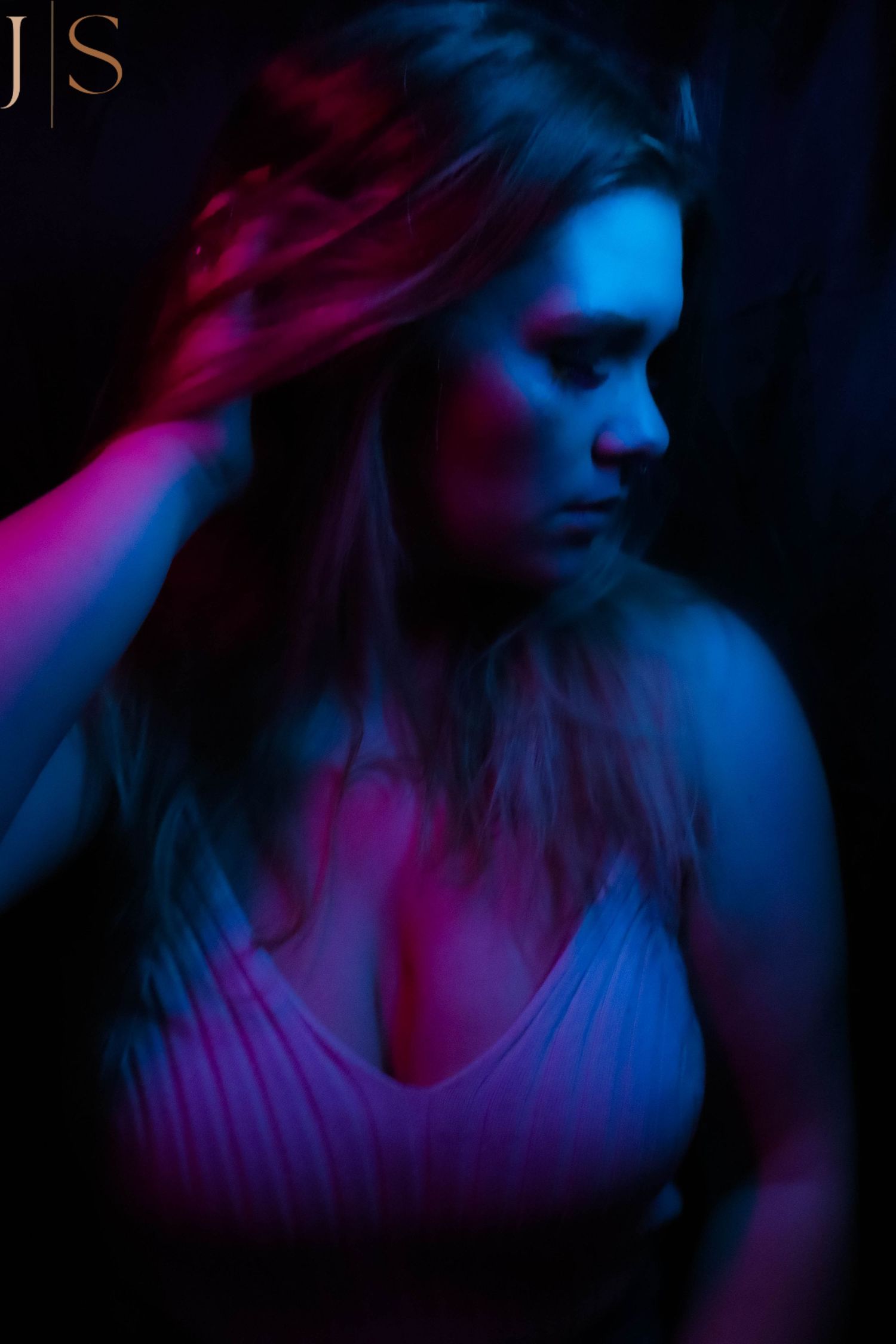 Atmospheric portrait with dramatic blue and pink lighting creating a moody nightclub aesthetic.