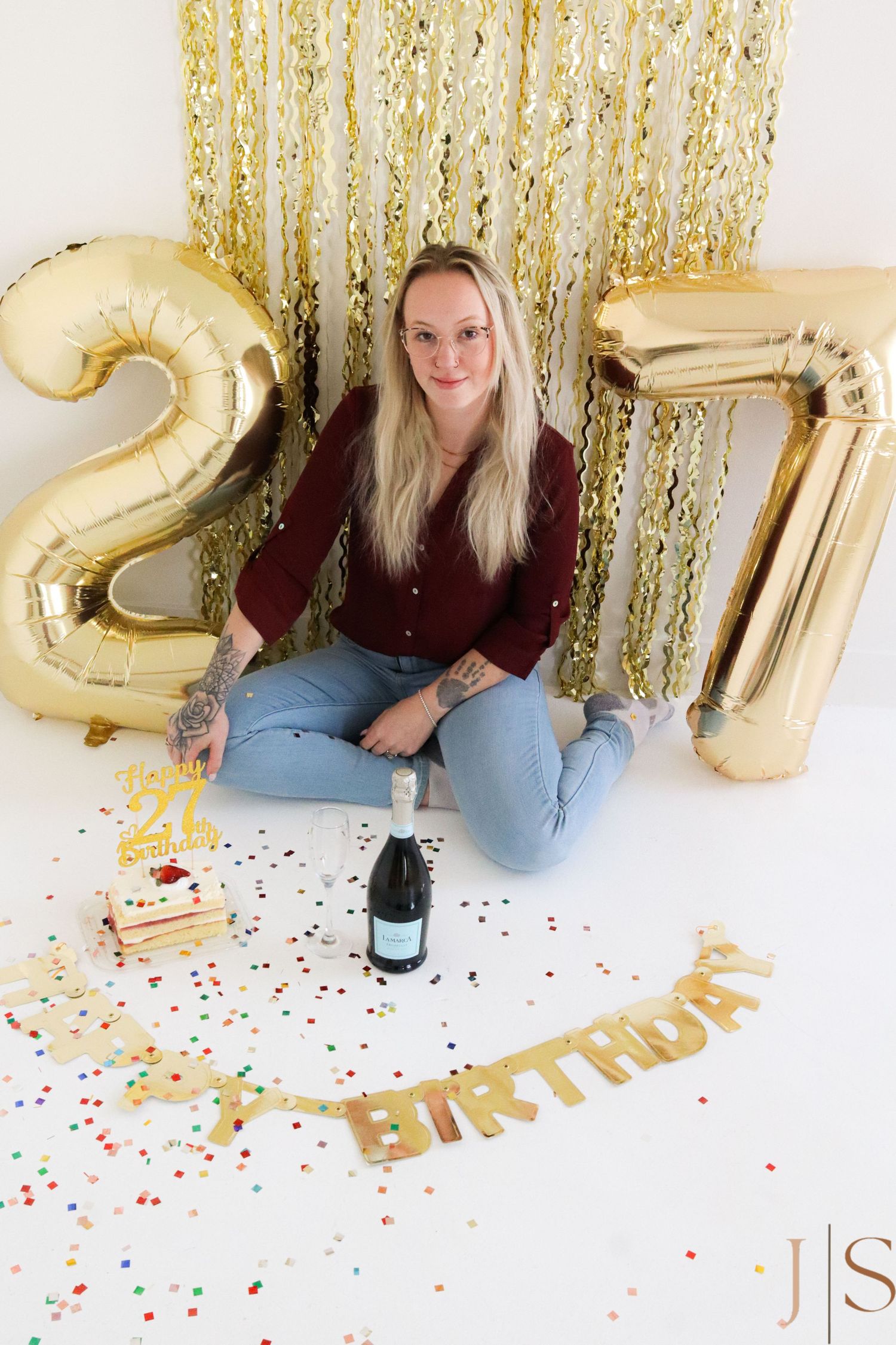 Birthday celebration scene with gold number balloons, champagne, confetti and festive gold streamers.