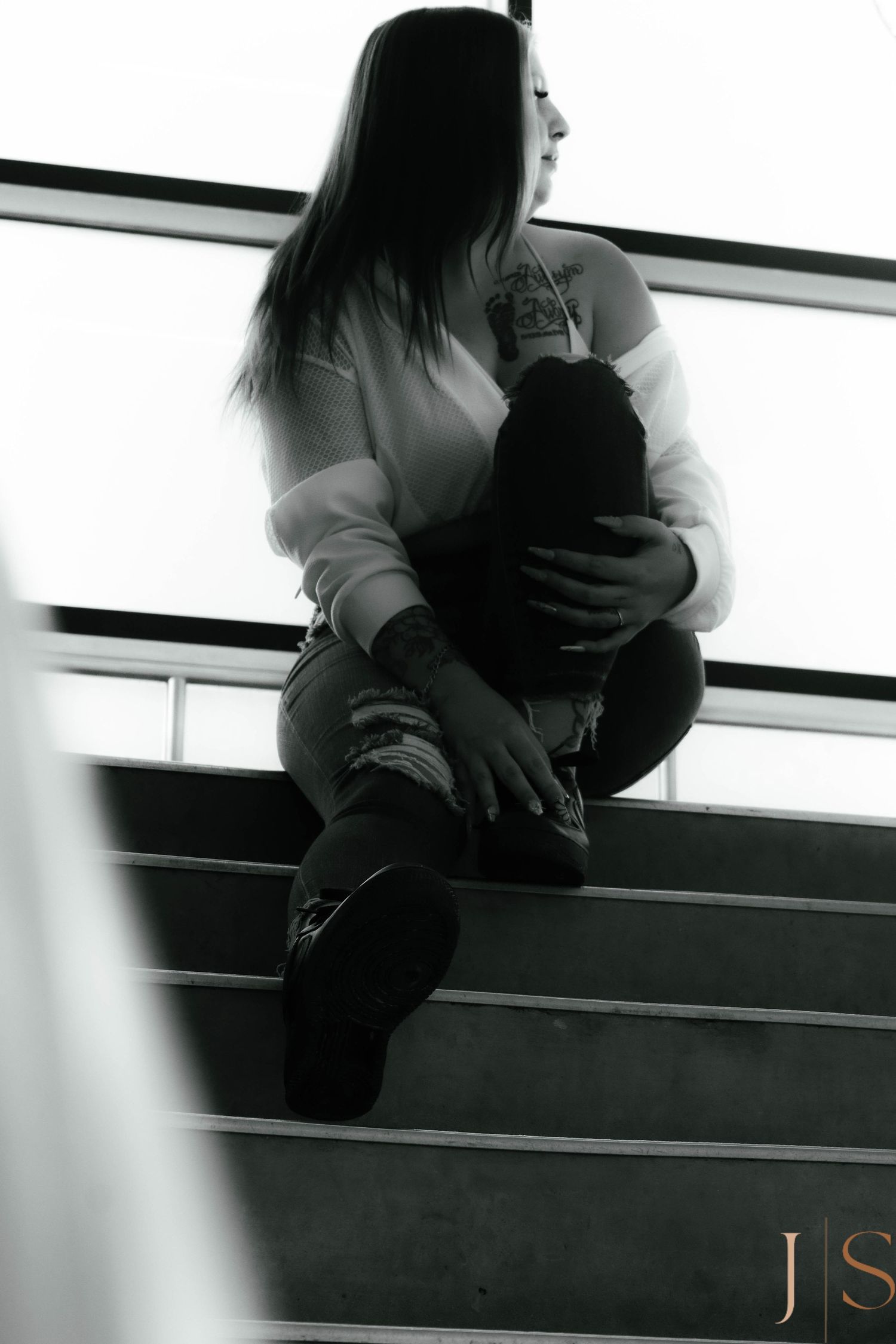 Person sitting alone on dark bleachers in contemplative pose.