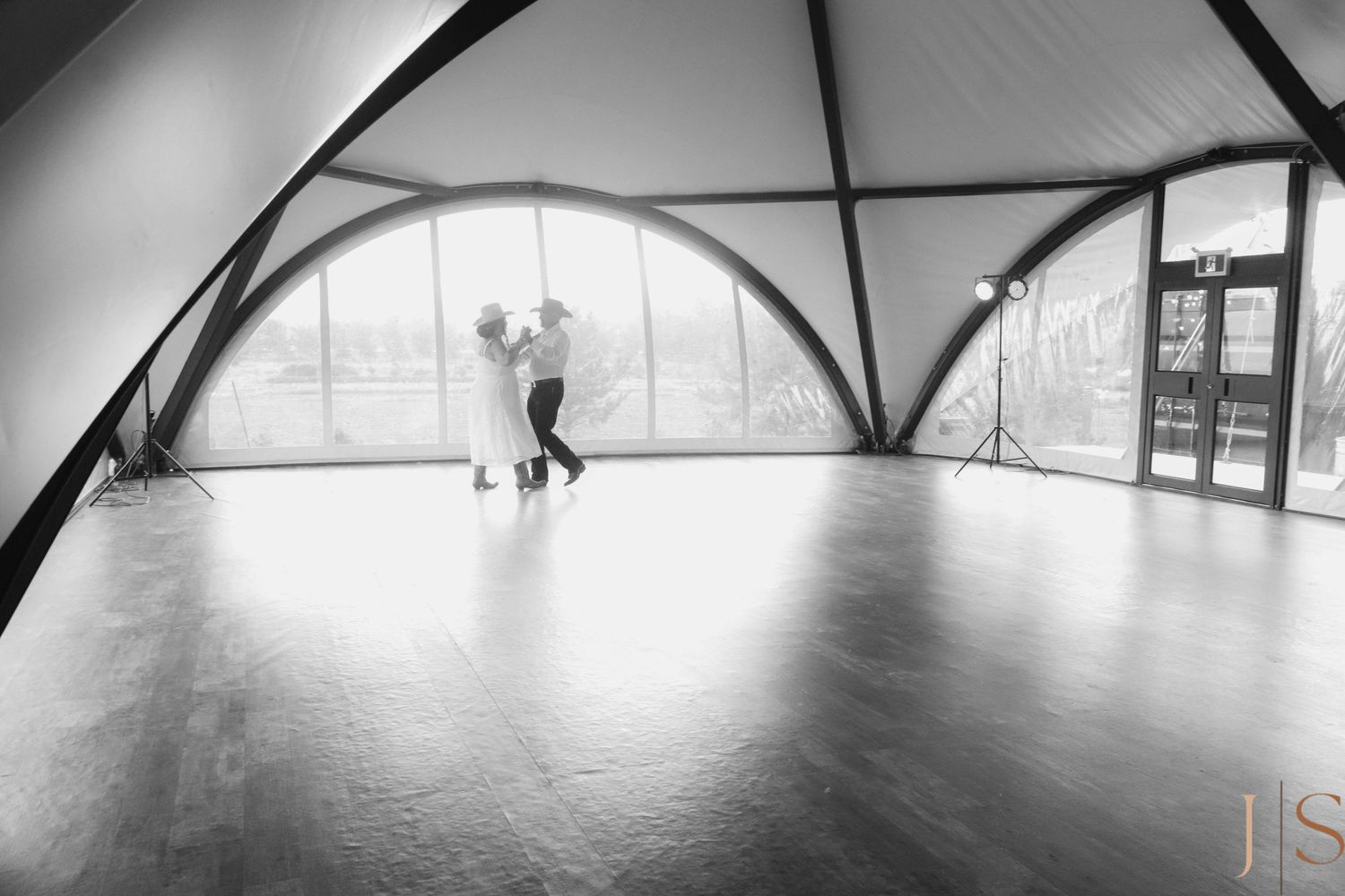 A graceful silhouette dances in a spacious dome-shaped studio with wooden floors and arched windows.