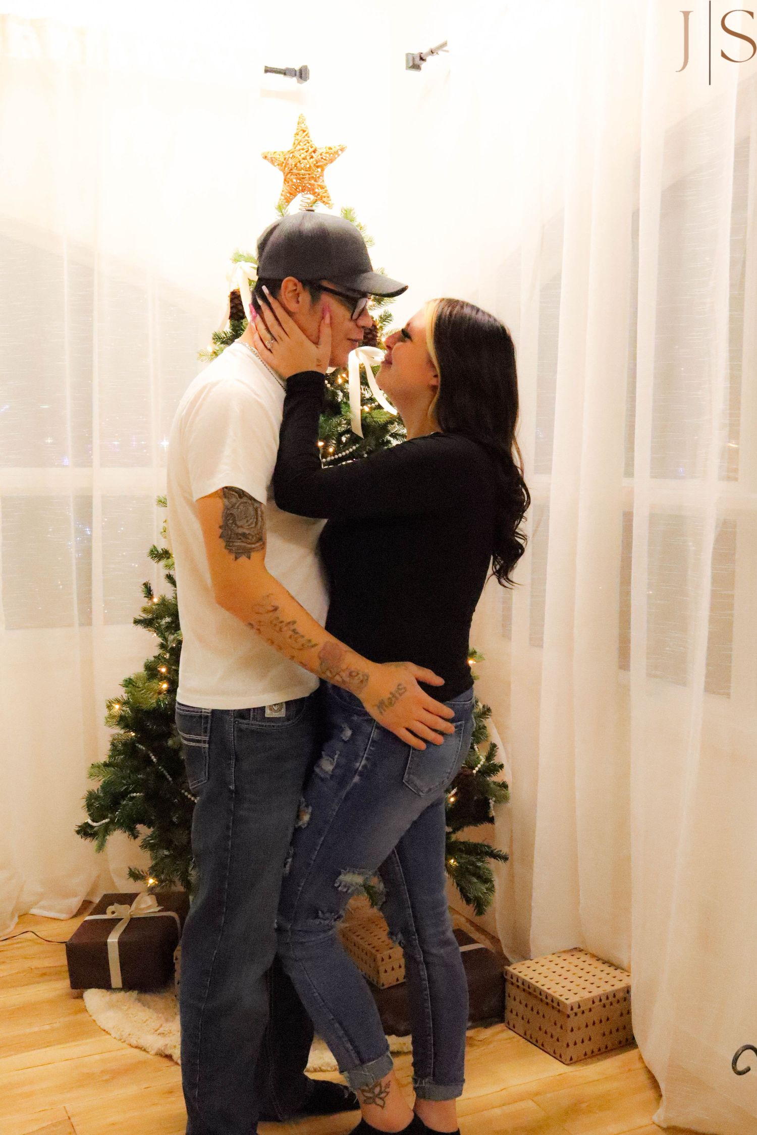 Couple dancing together in a cozy living room decorated for the holidays with a Christmas tree and gifts.