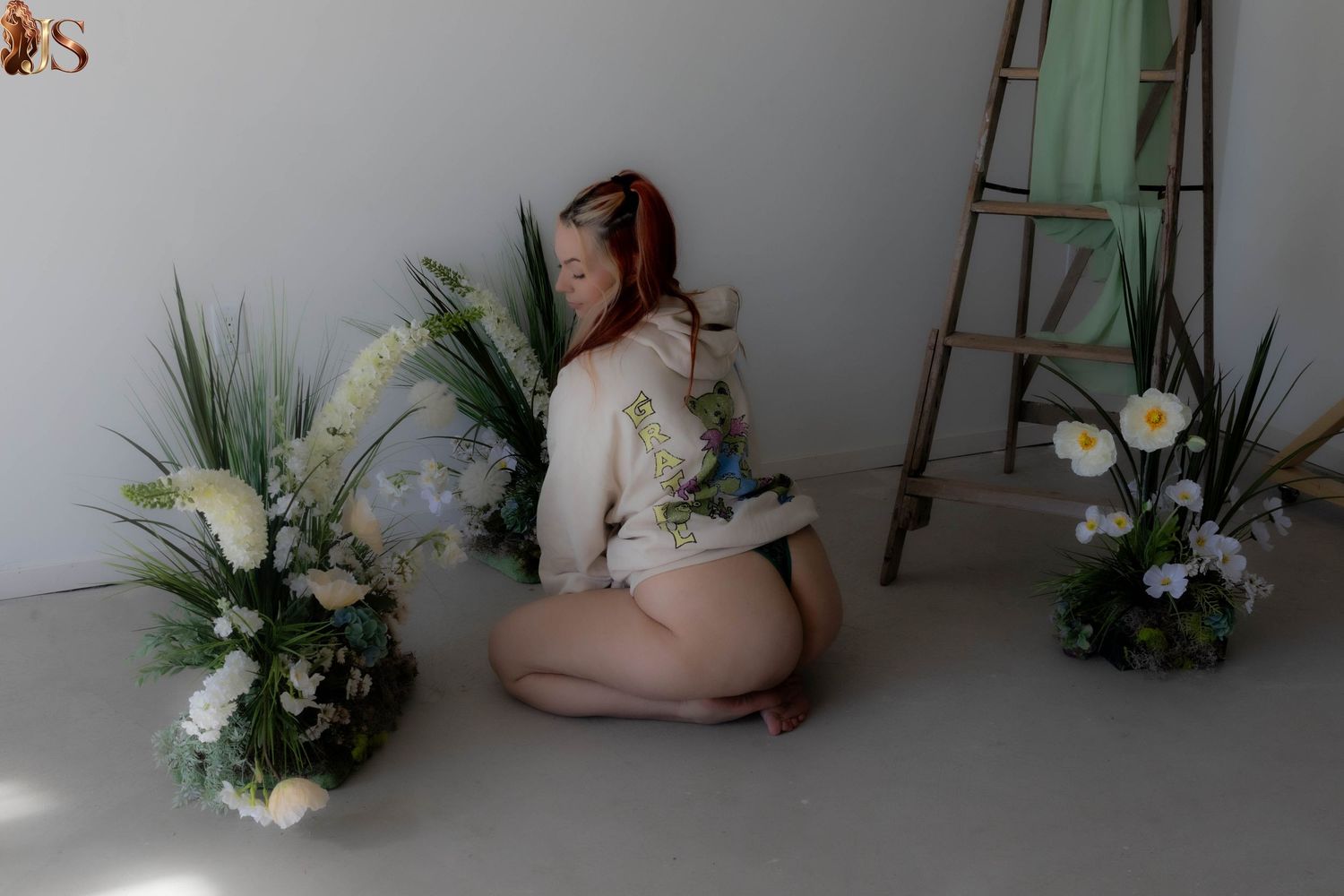 Artistic boudoir photo series showing floral arrangements and soft lighting against a light gray wall.