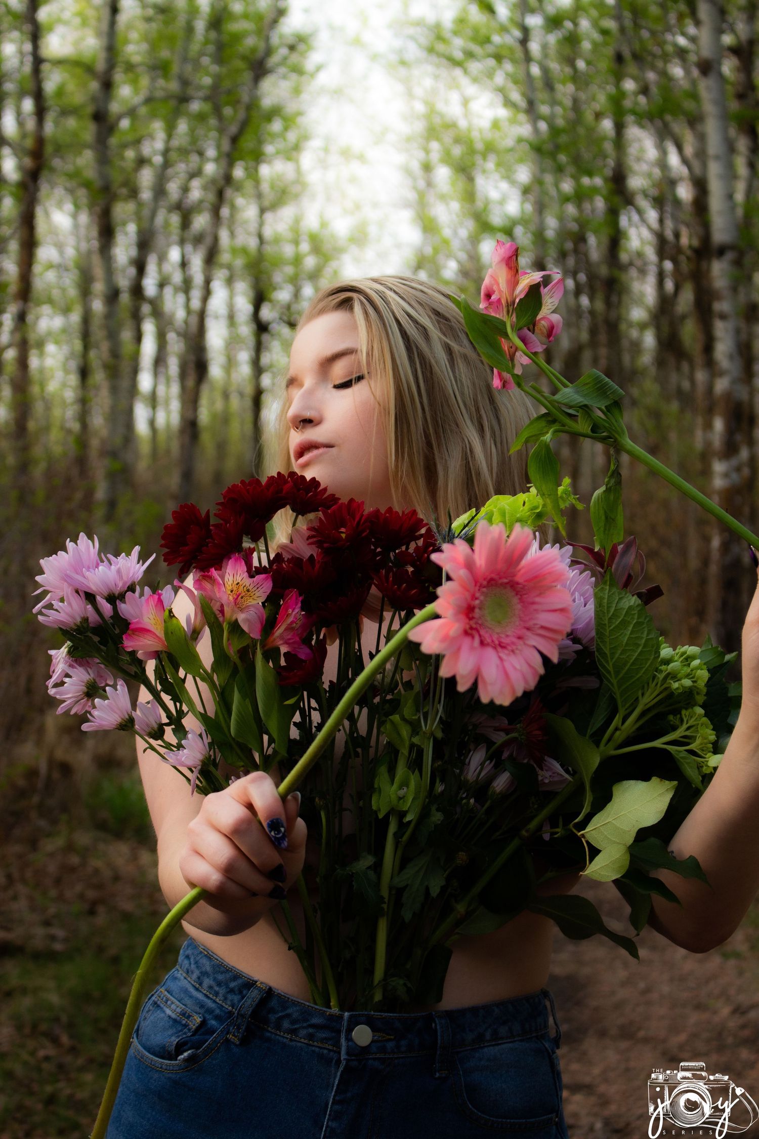 A dreamy forest portrait showcasing vibrant gerbera daisies and burgundy flowers against a soft woodland background.