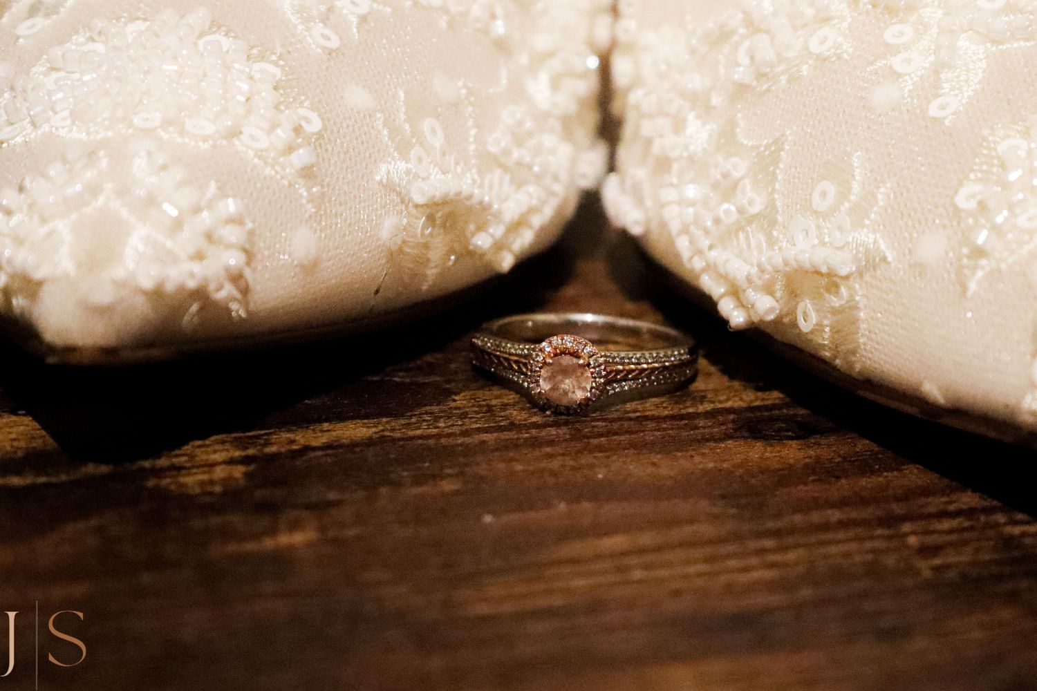 A sparkling diamond engagement ring photographed between white fabric on a rustic wooden surface.