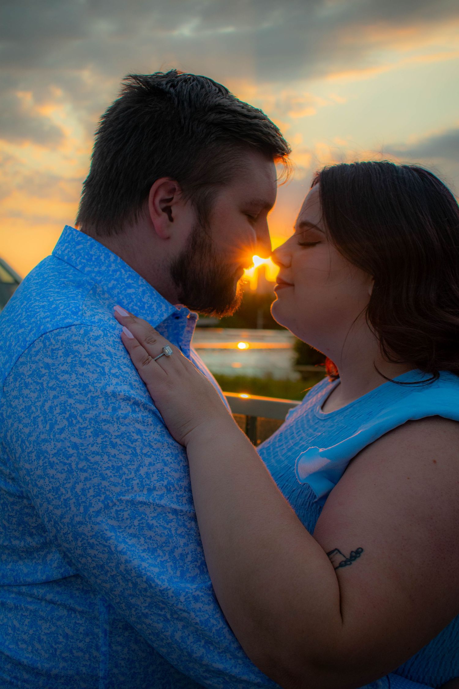 Intimate couple portrait against dramatic sunset sky.