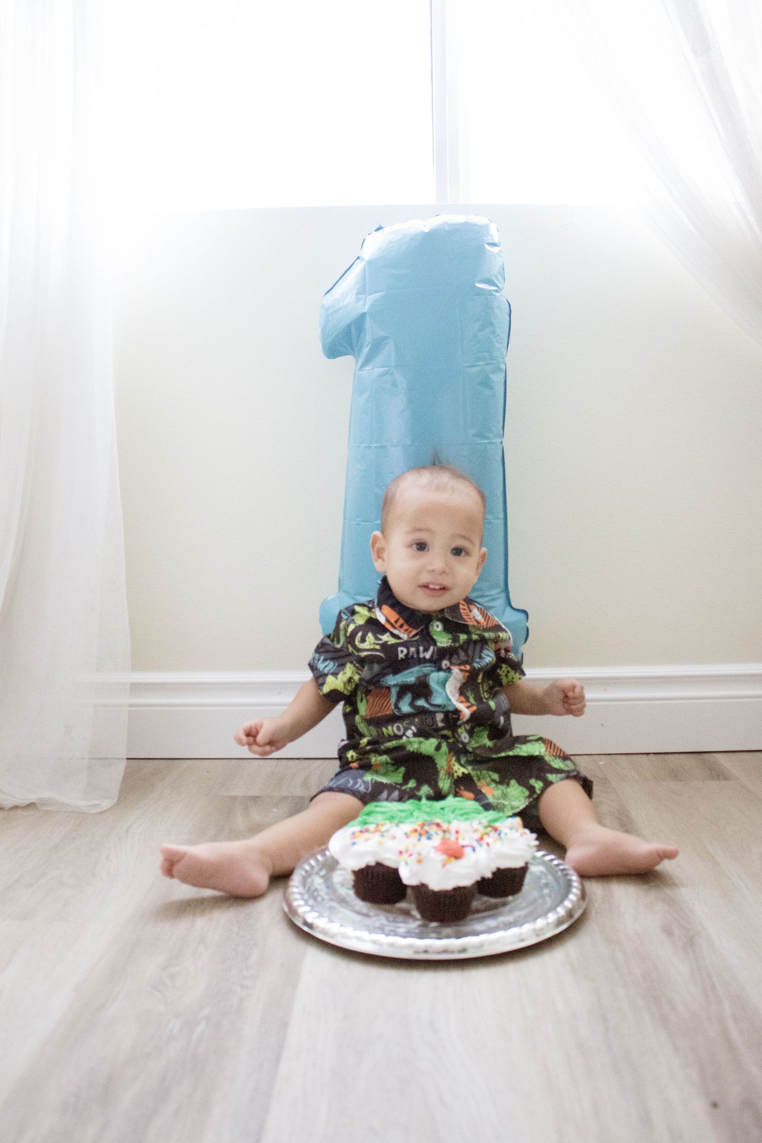 A first birthday celebration setup with a large blue number one balloon and decorated cake.