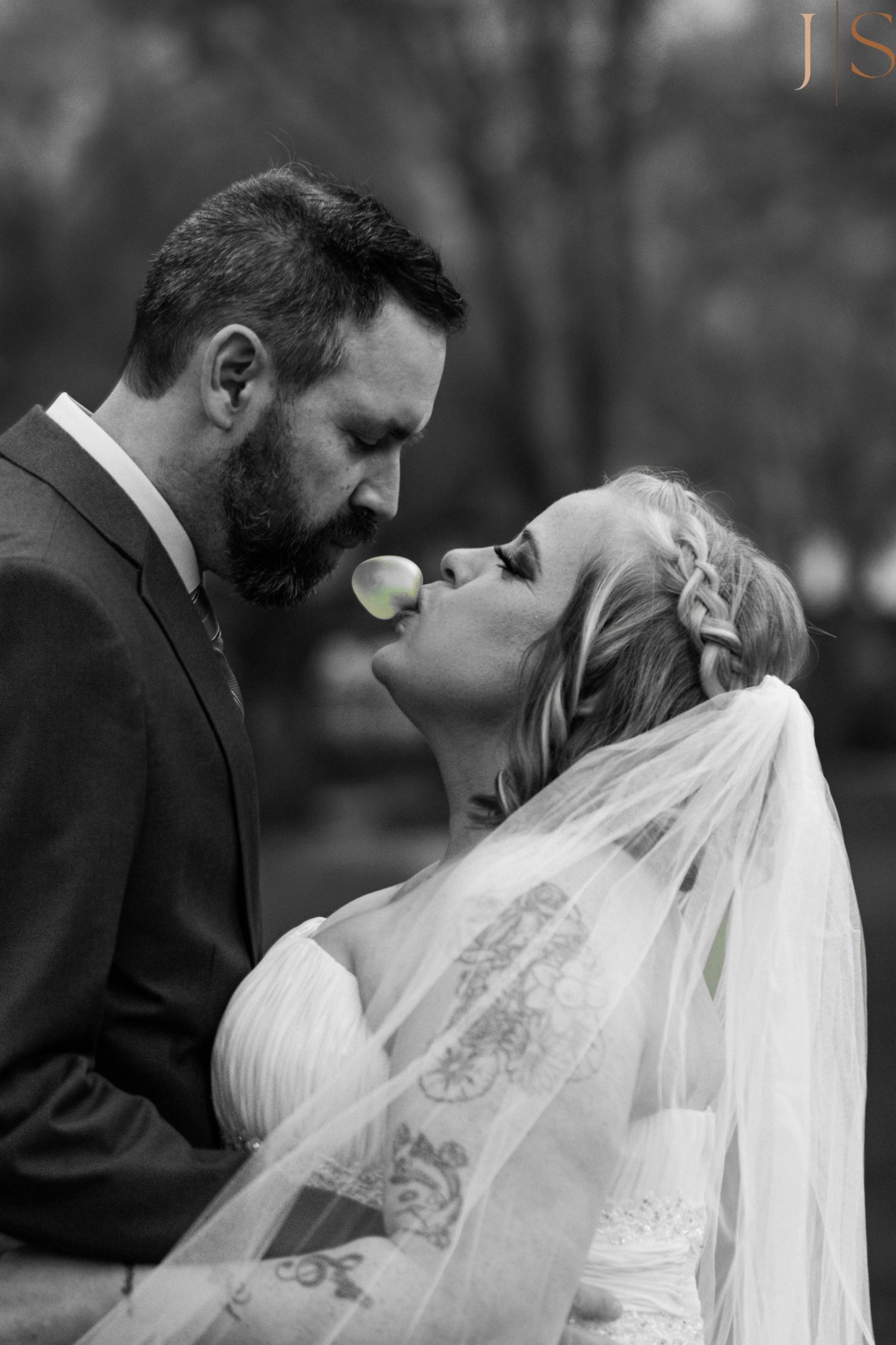 A black and white wedding photo of a couple sharing an intimate moment with a lime slice between them.