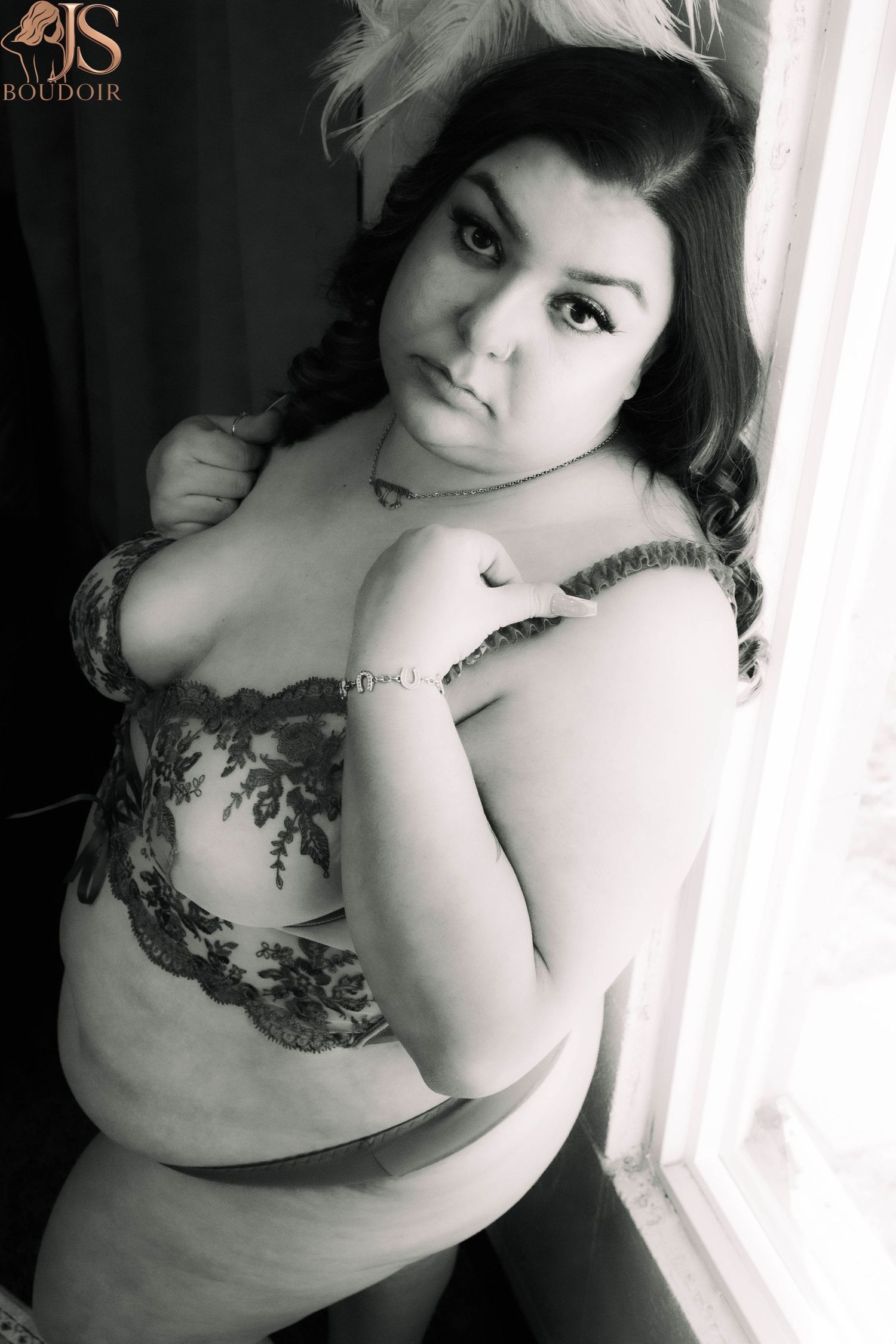 Black and white boudoir portrait featuring lace lingerie against a window backdrop.