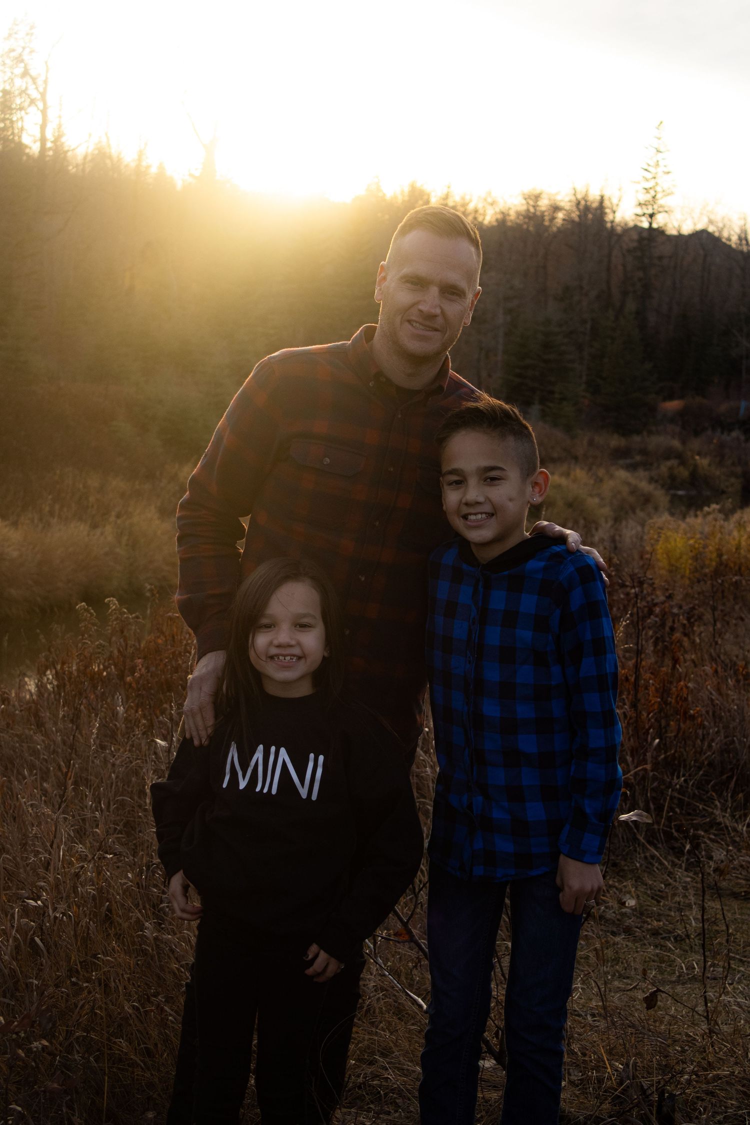 A heartwarming family portrait in nature during golden hour with mountains in the background.