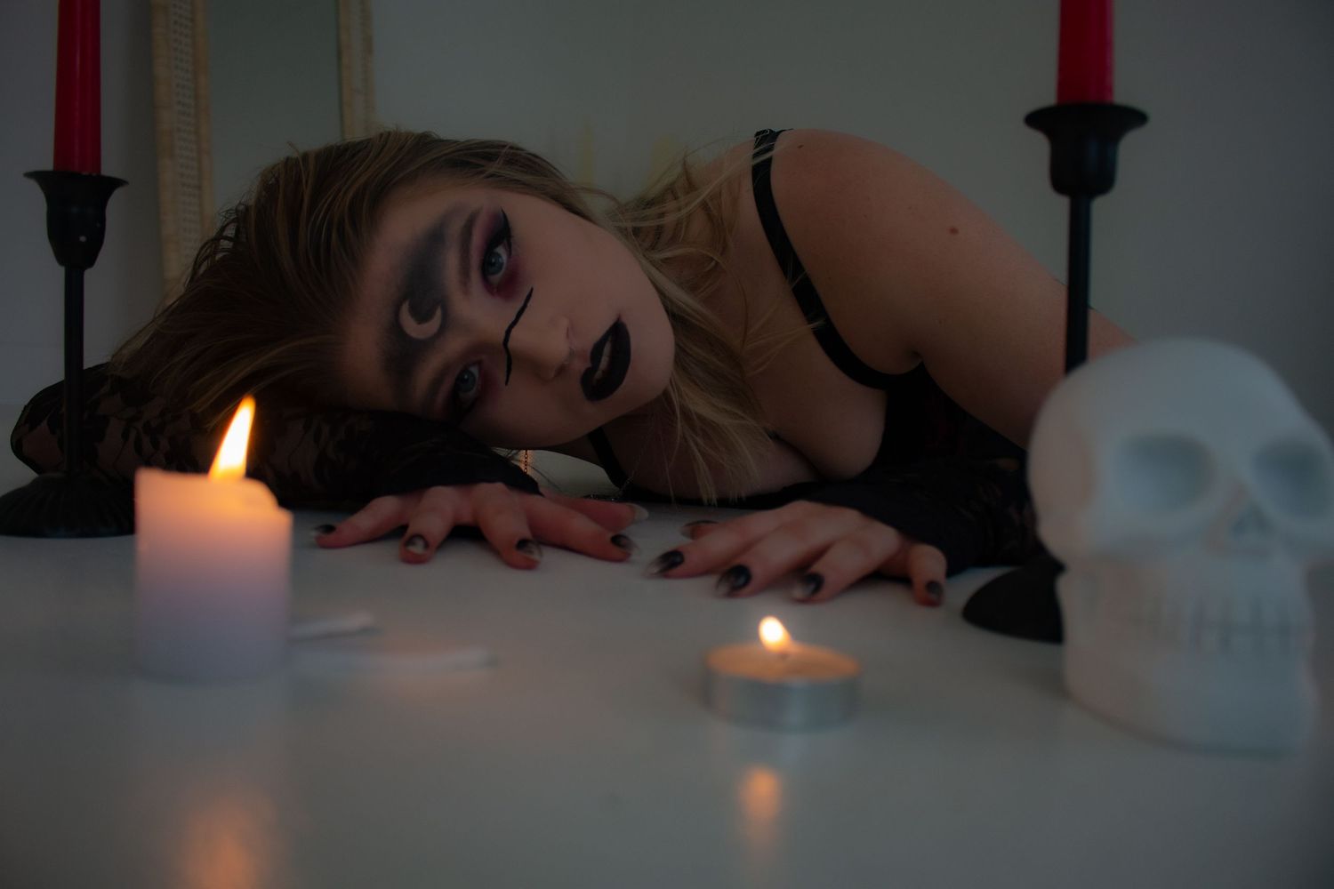 Moody scene with candles and skull decorations on table with dramatic lighting.