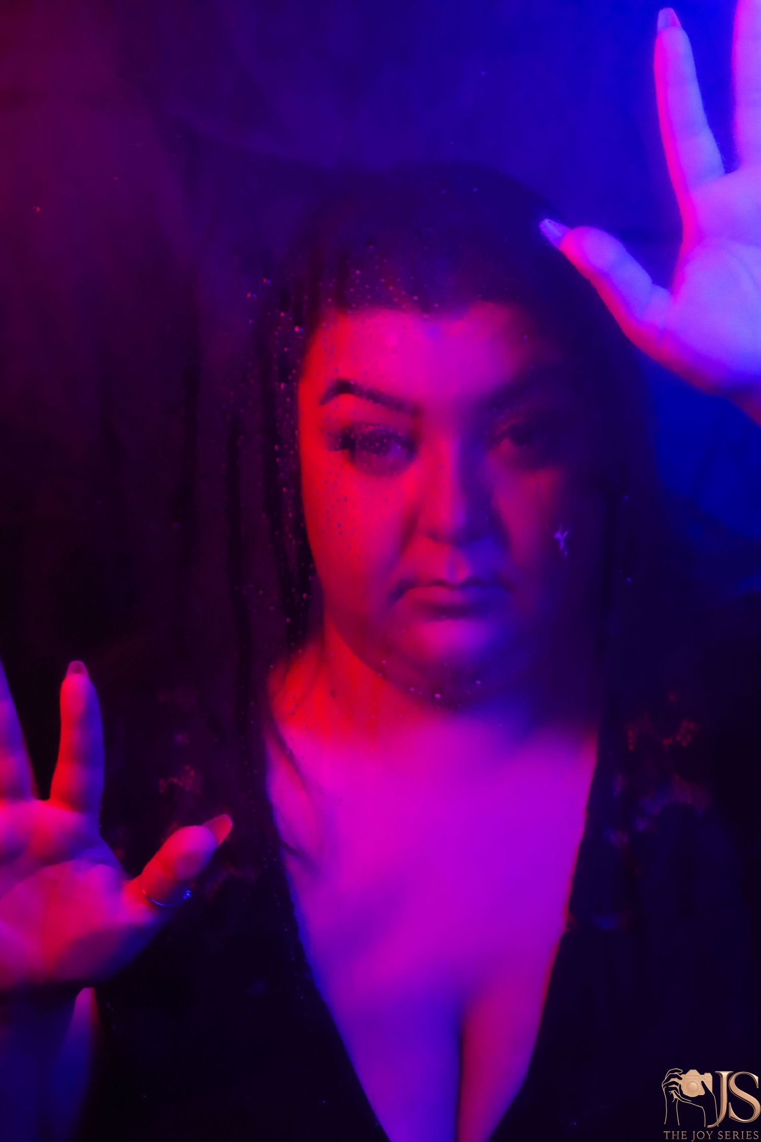 Dramatic neon-lit portrait bathed in vibrant red and blue lighting creating a moody nightclub atmosphere.