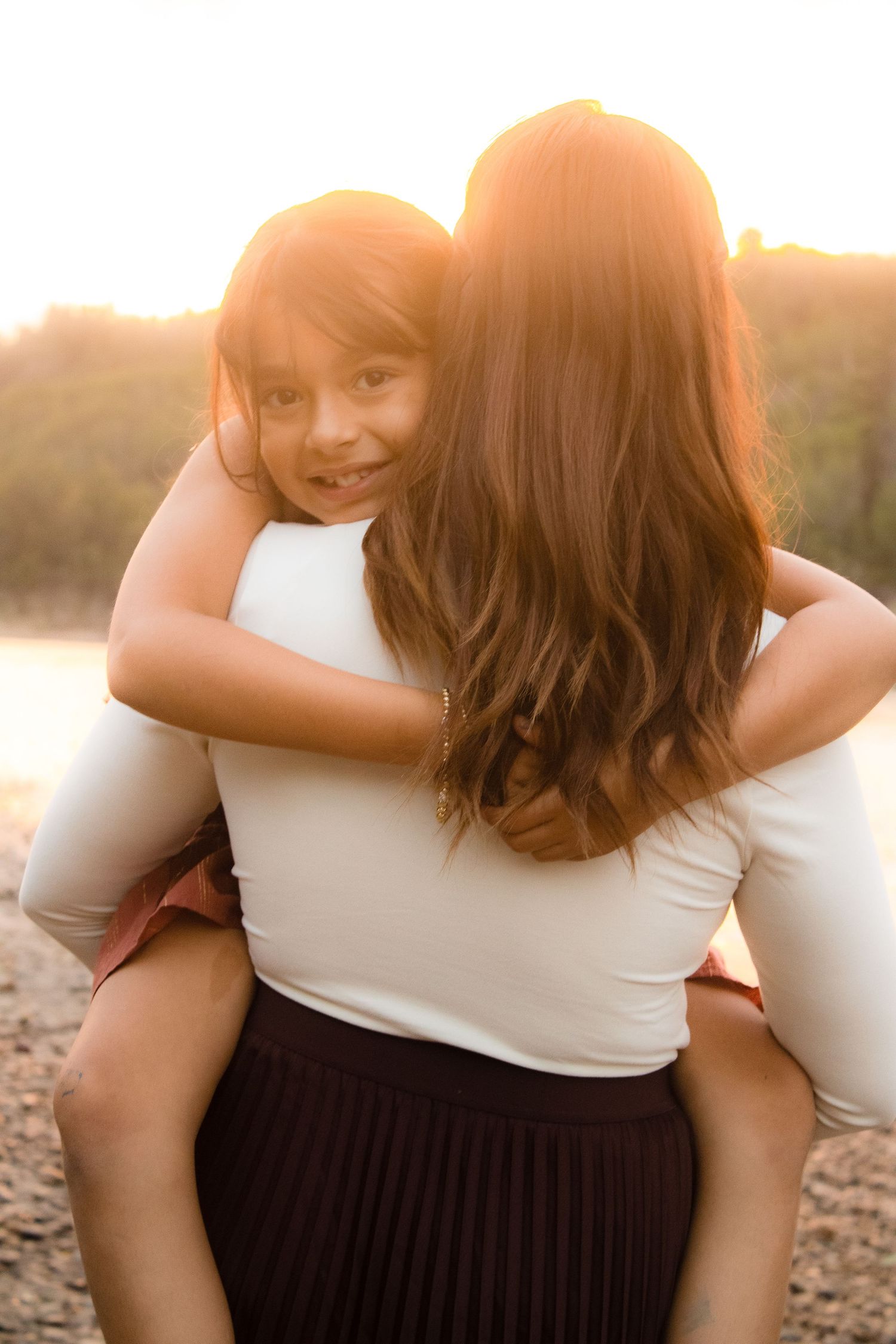 A tender piggyback moment captured in warm sunset lighting.