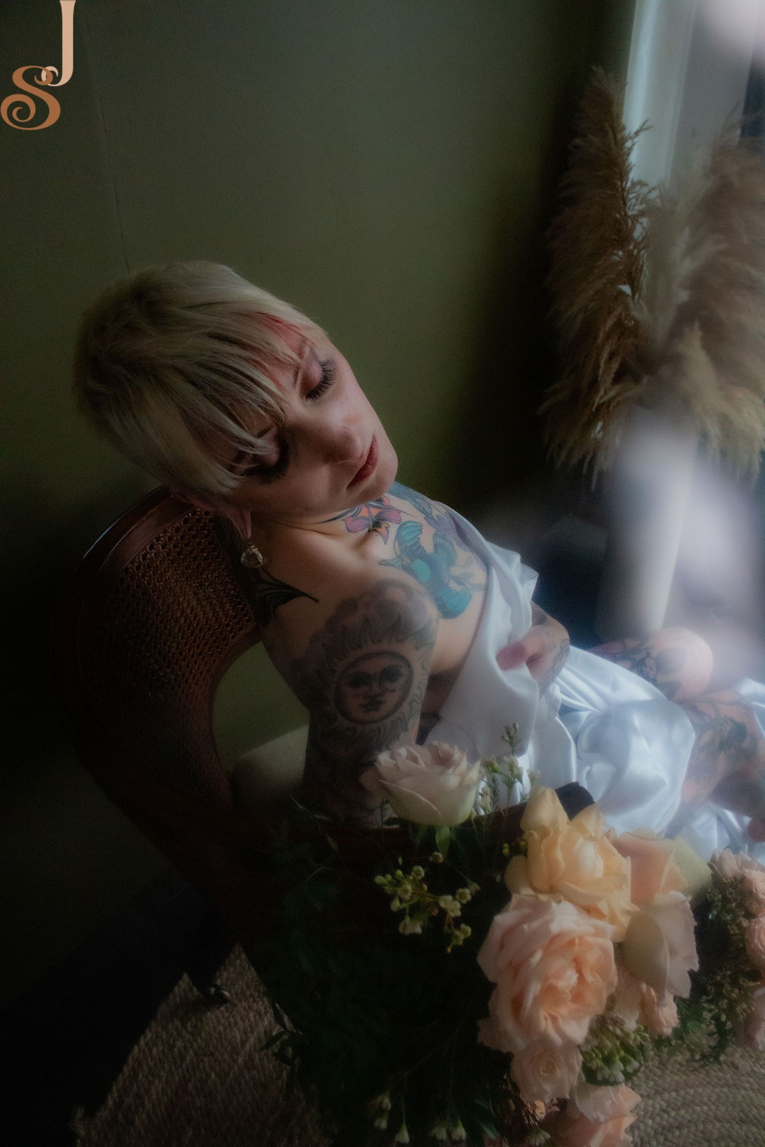 Dreamy artistic portrait in soft lighting with peach roses on a textured surface near a window.