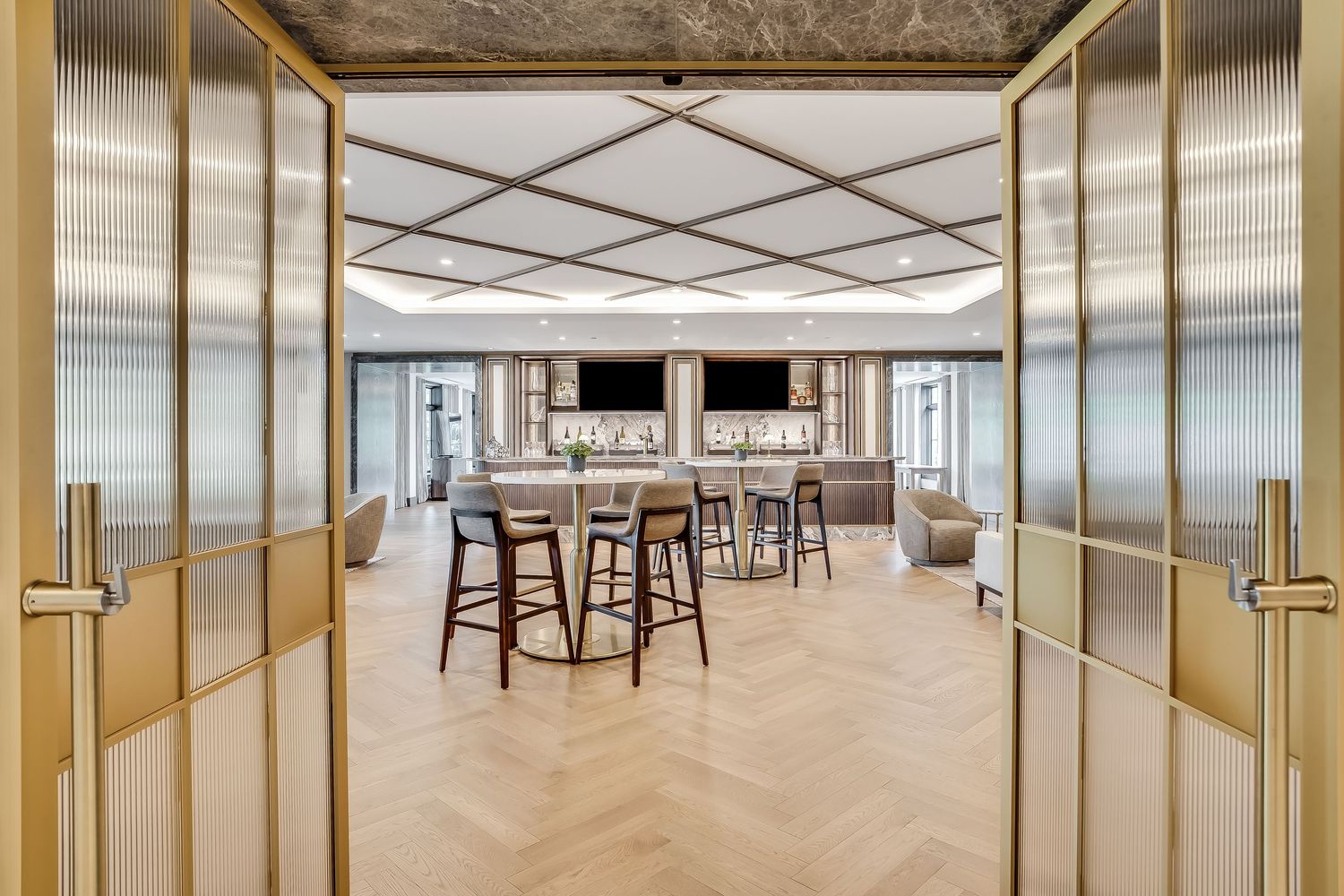 Modern office interior with wood floors, glass walls, and suspended ceiling featuring contemporary lighting and seating areas.