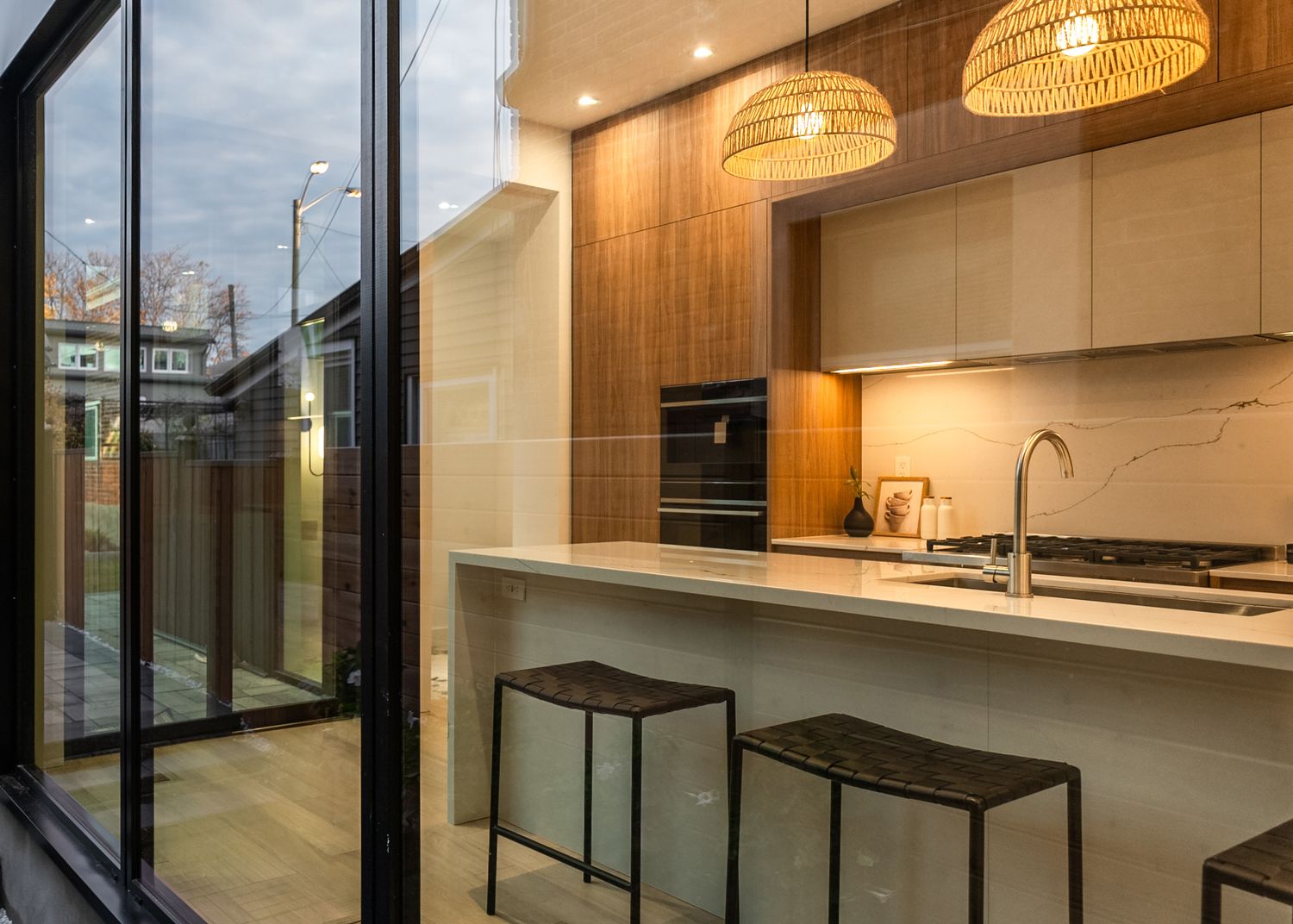 Modern kitchen interior with bamboo pendant lights and sleek white cabinetry showcases clean minimalist design.