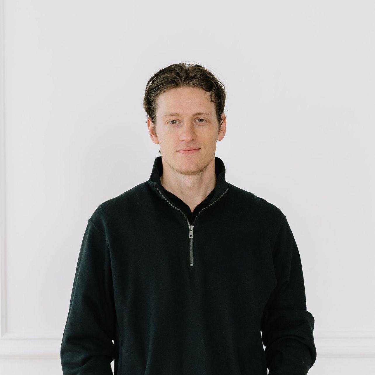 Person wearing black zip-up hoodie shown in four similar poses against white background.