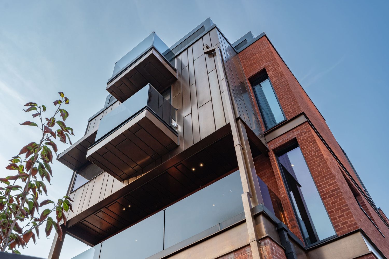 Modern residential building exterior featuring brick and metal cladding with dramatic angular architectural details.