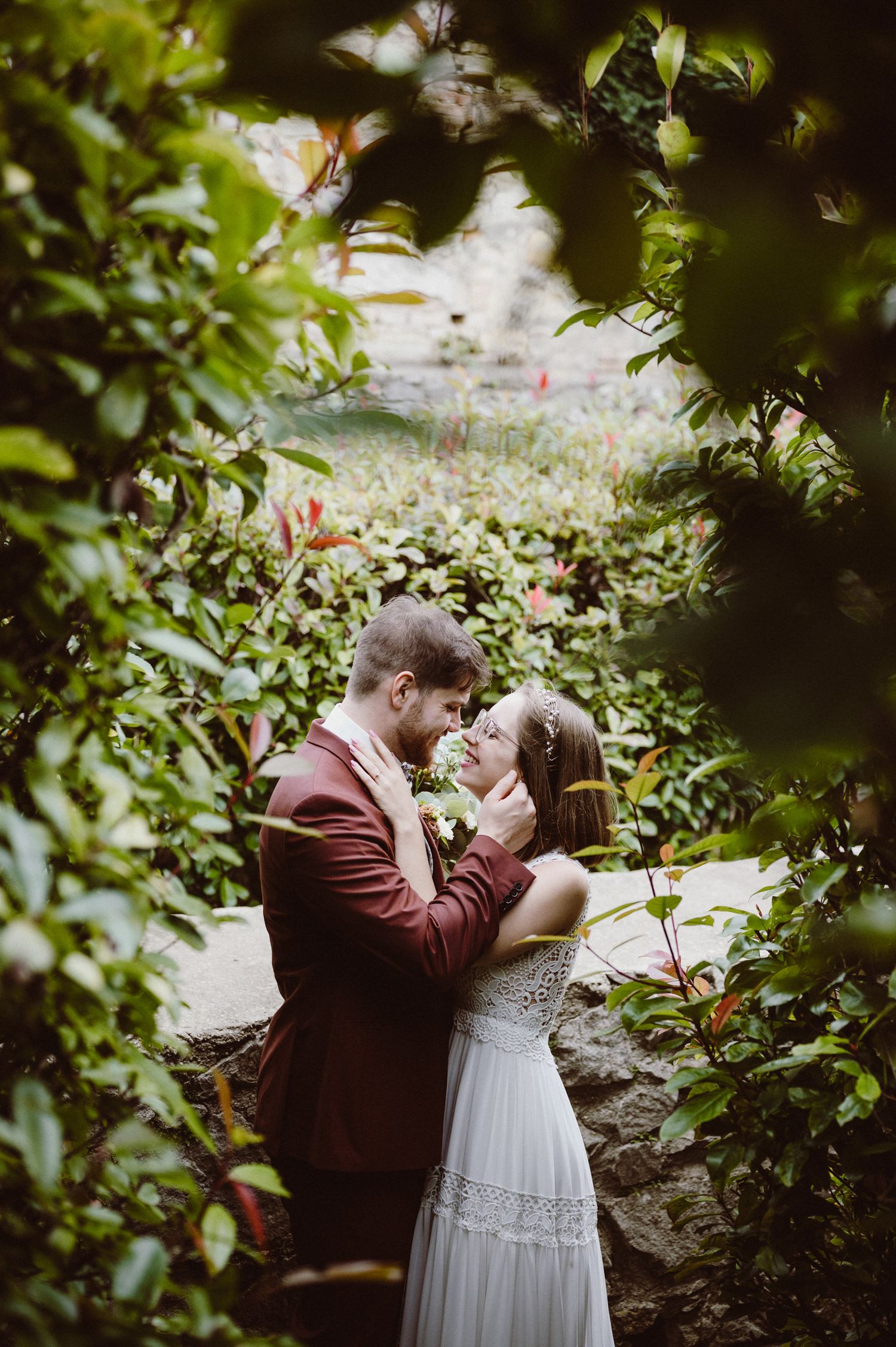 A couple shares an intimate moment together in a lush garden setting during their wedding photoshoot.