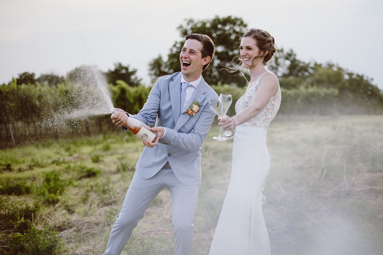 Happy couple laughs and dances together during outdoor photo session in misty natural setting.