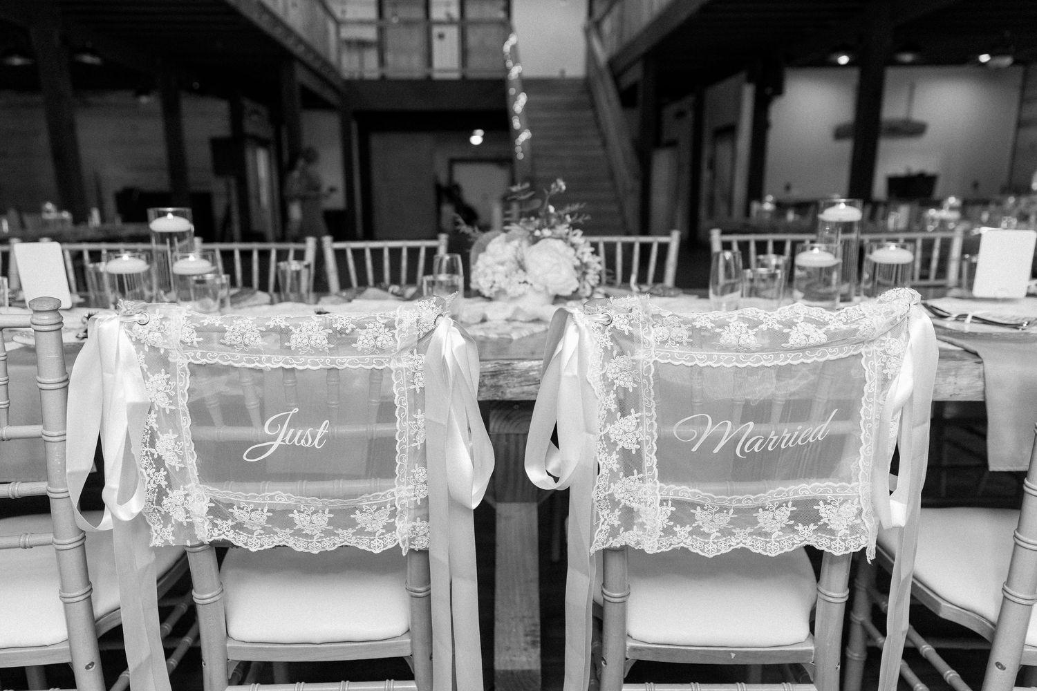 Black and white photo of Just Married lace chair signs at elegant wedding reception venue.