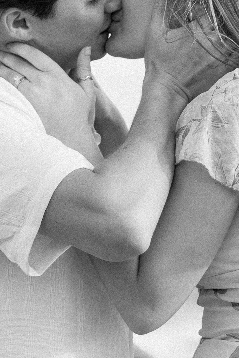 Black and white photo of a couple sharing a romantic kiss, embracing each other tenderly.