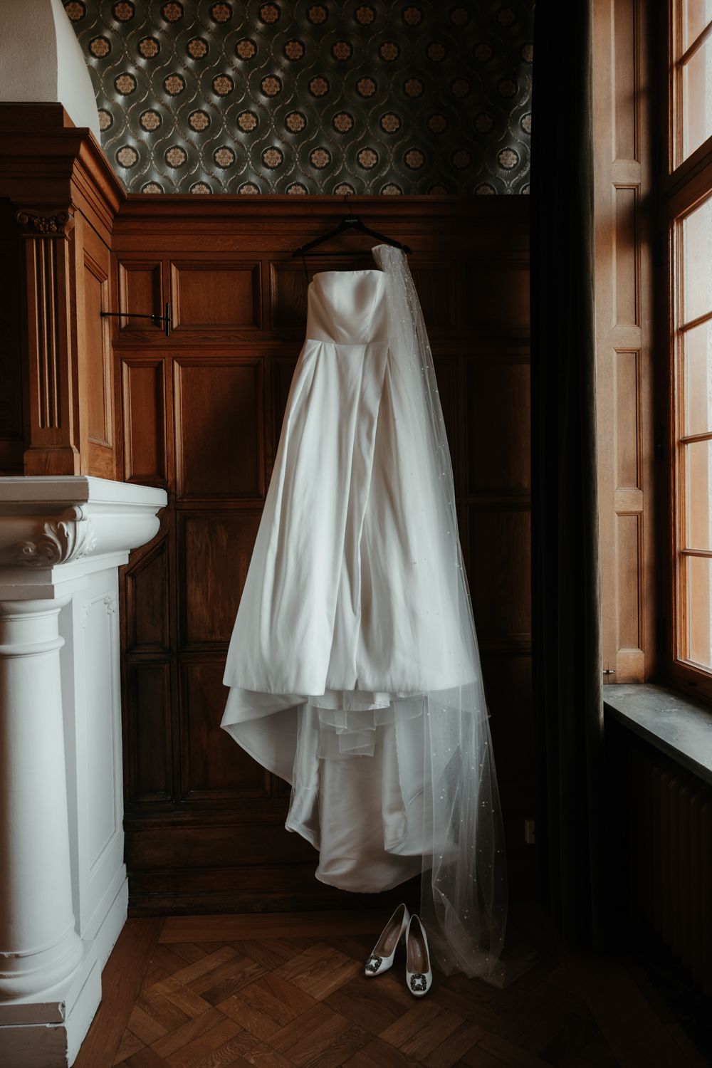 Elegant brudklänning hänger på väggen på Maryhill Estate under en bröllopsdag förevigad av Grevholm Photography.