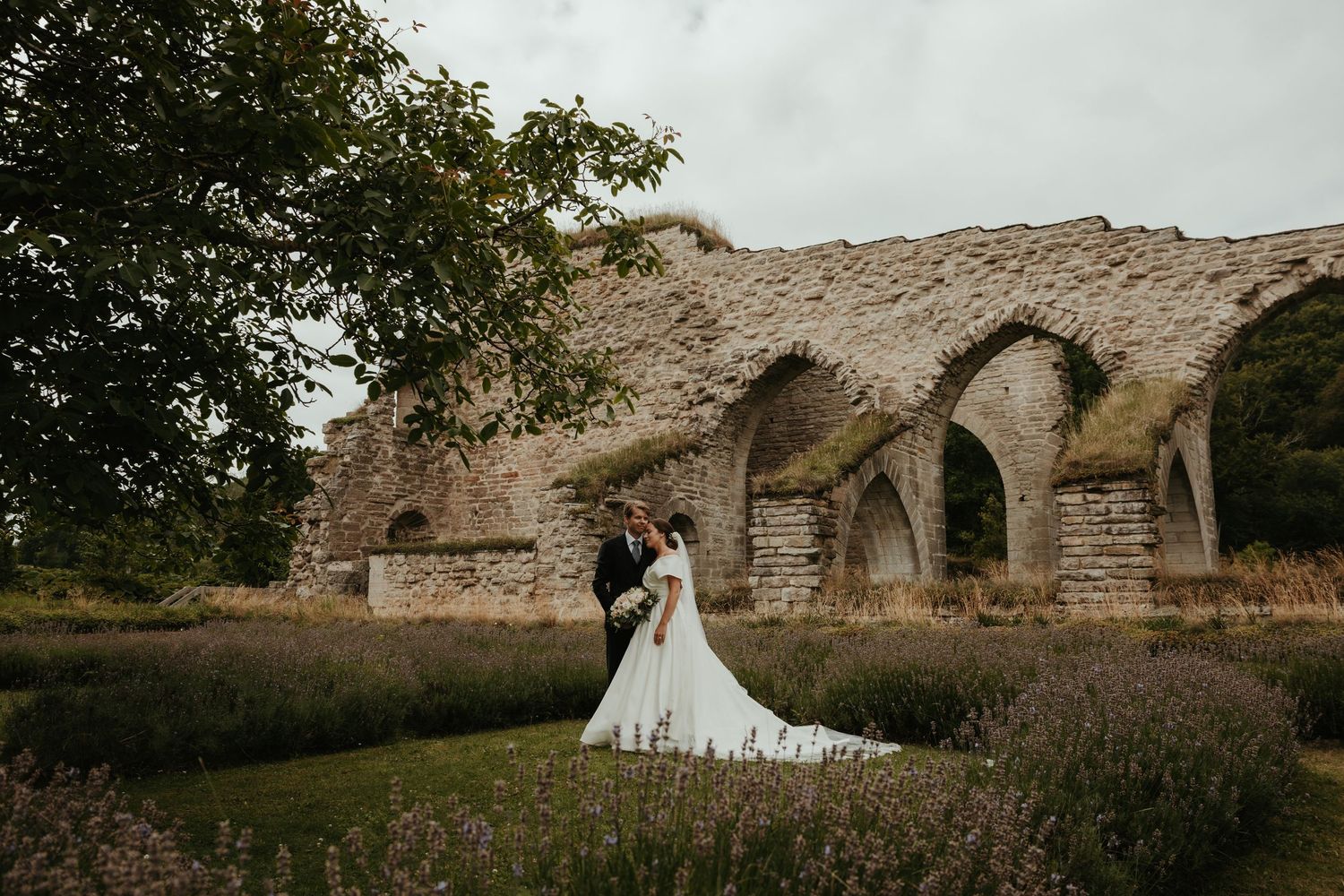 Brudpar poserar framför Alvastra Kloster. Foto: Grevholm Photography.