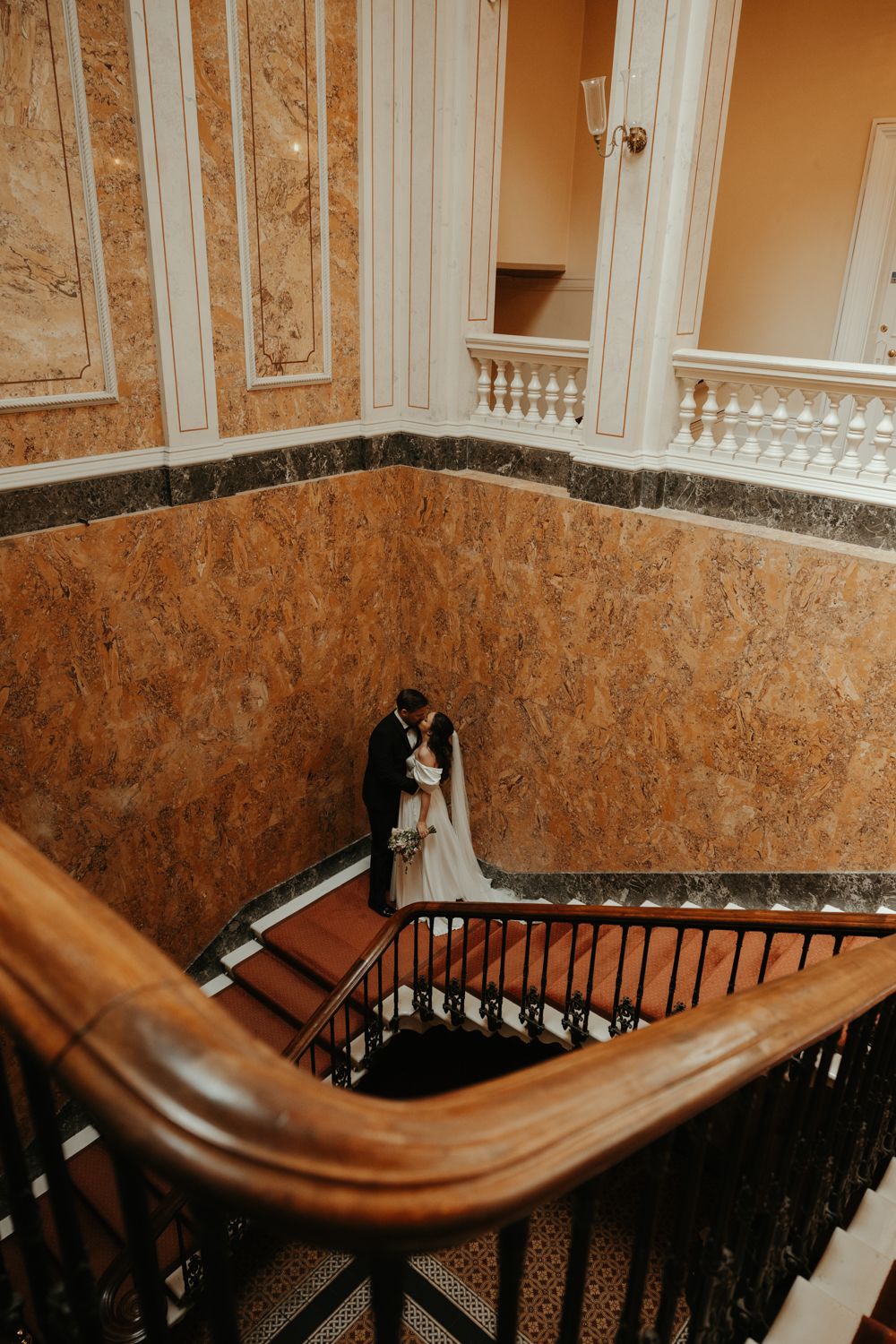 Brudpar står i trappan på Överås slott i Göteborg på deras bröllop. Fotograf Grevholm Photography.