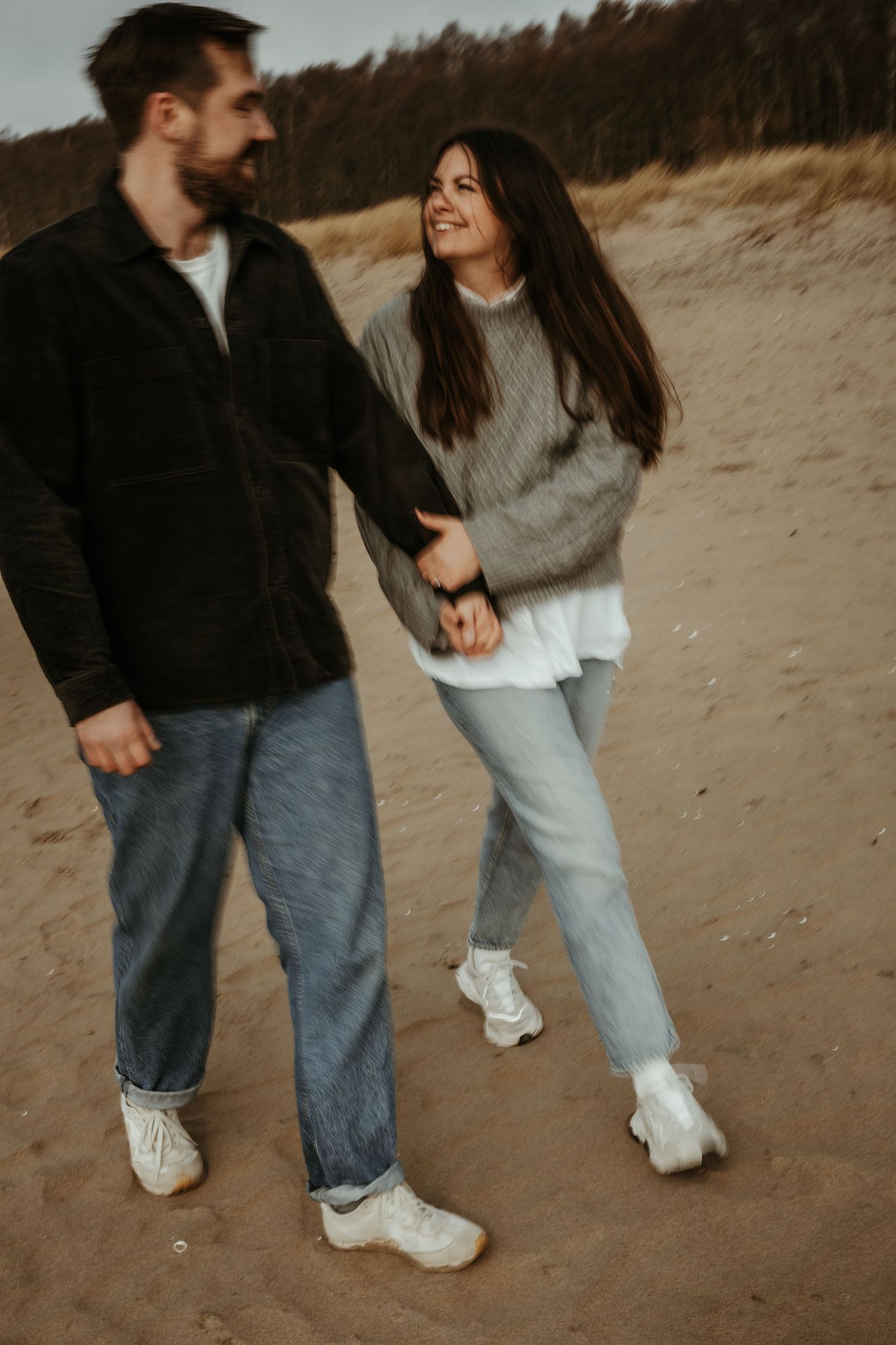 En bild med rörelseoskärpa på ett par som går hand i hand på en strand i Halmstad under en parfotografering med Grevholm Photography