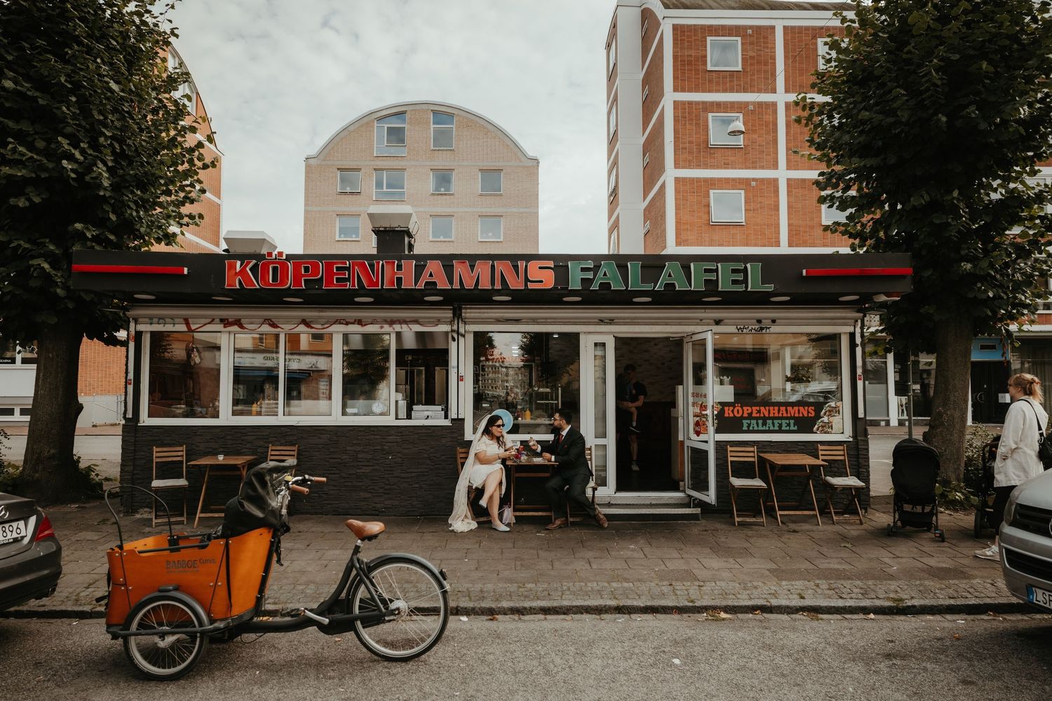 Ett brudpar sitter utanför ett gatukök i Malmö och äter falafel. Foto av Grevholm Photography.