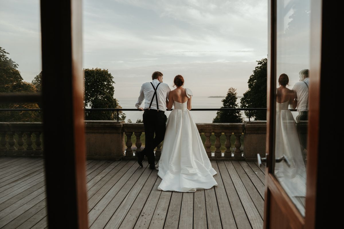 Brudpar tar en paus på balkongen under deras bröllop på Maryhill Estate fotograferat av Grevholm Photography.