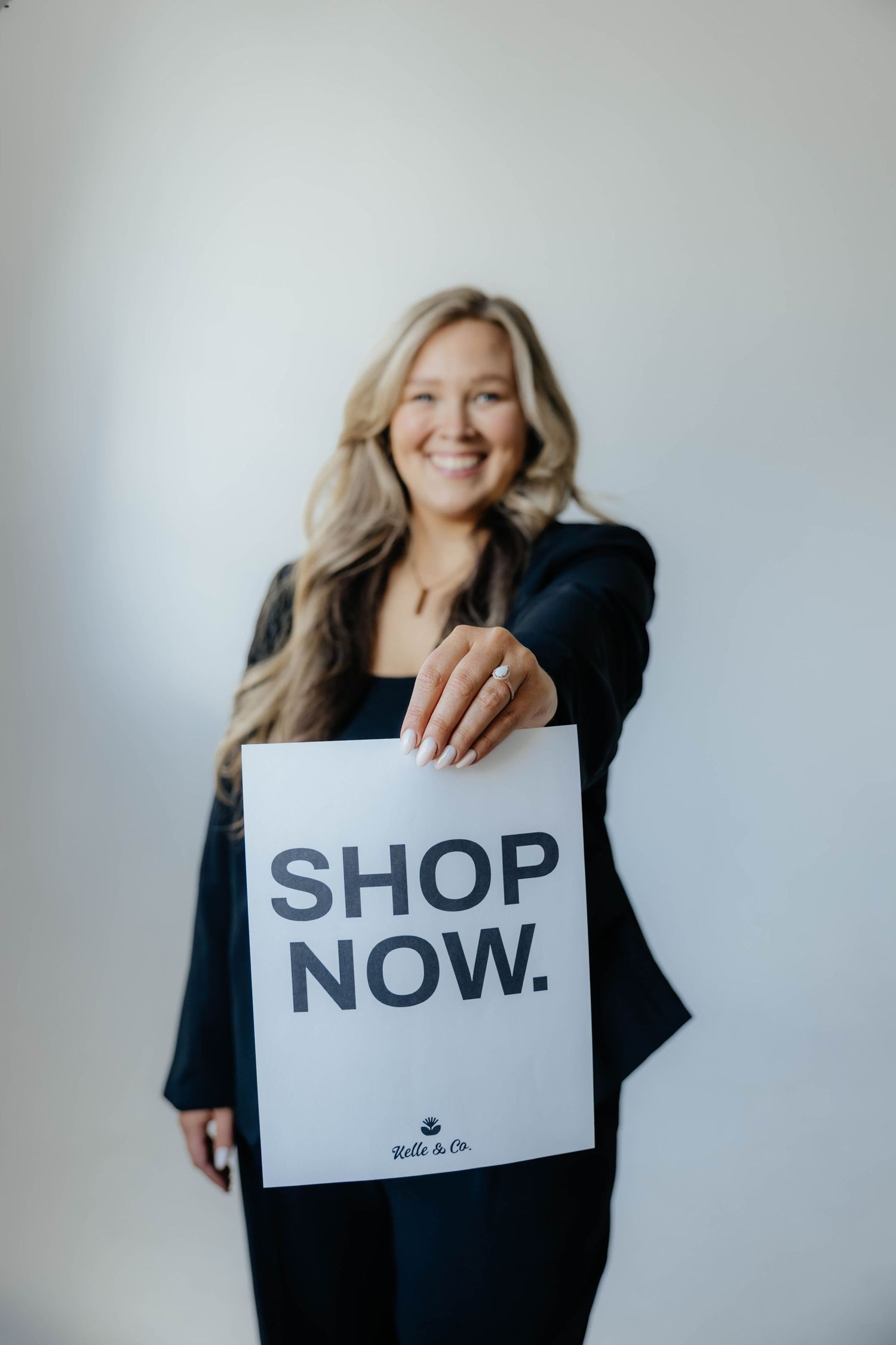 Studio portraits featuring someone holding signs that say SHOP and NOW against white backdrop.