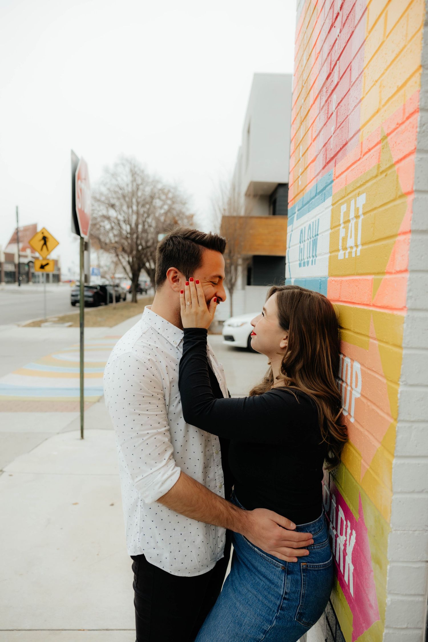 Couple sharing intimate moments against a colorful graffiti wall in an urban setting.