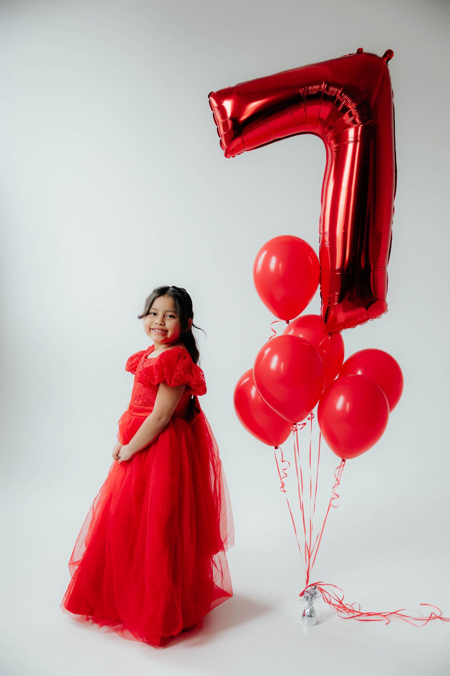 Festive photo shoot with red tulle dress and matching number 7 balloon.