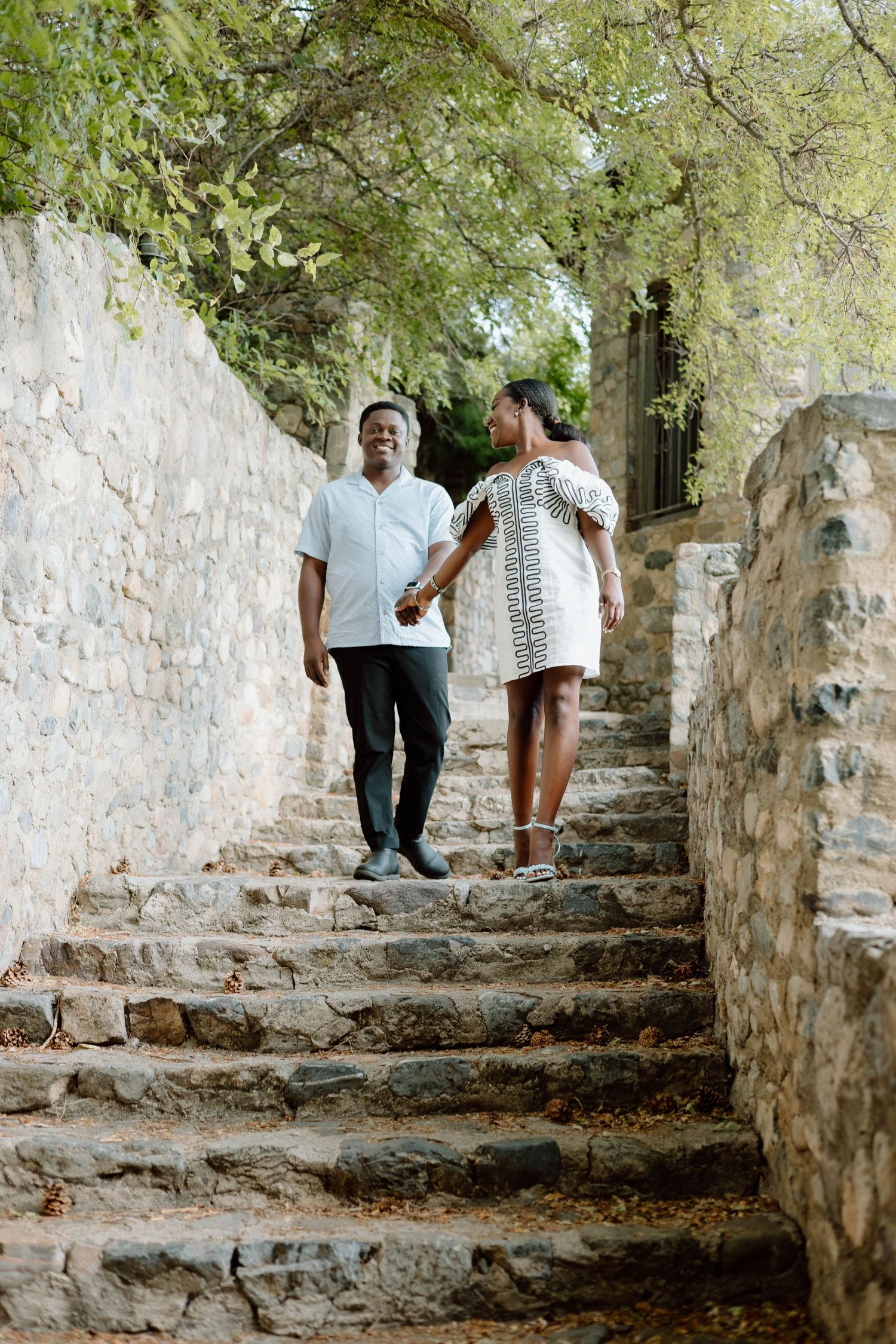 Family walking up stone steps surrounded by lush greenery and ancient walls.