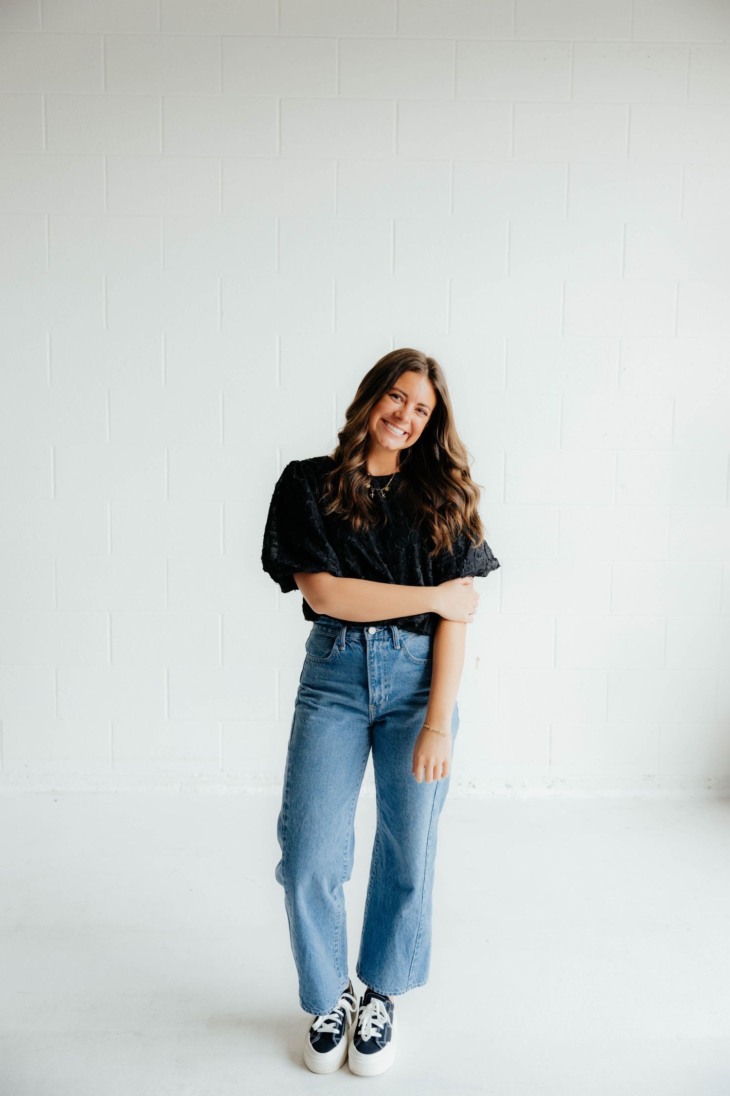 Lifestyle photography session showing casual poses in jeans and black top against white background.