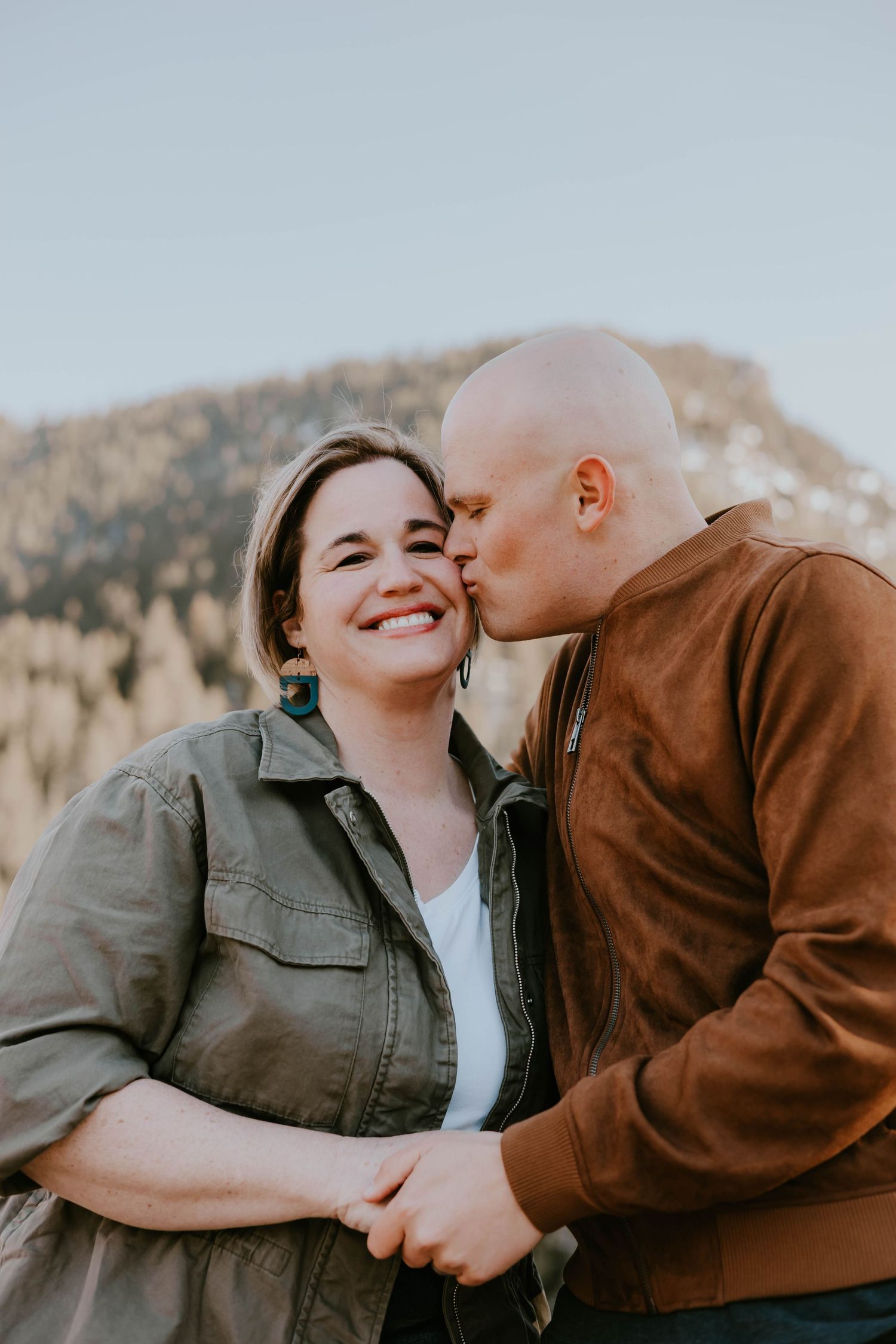 Intimate couple sharing a tender moment against a mountain backdrop.