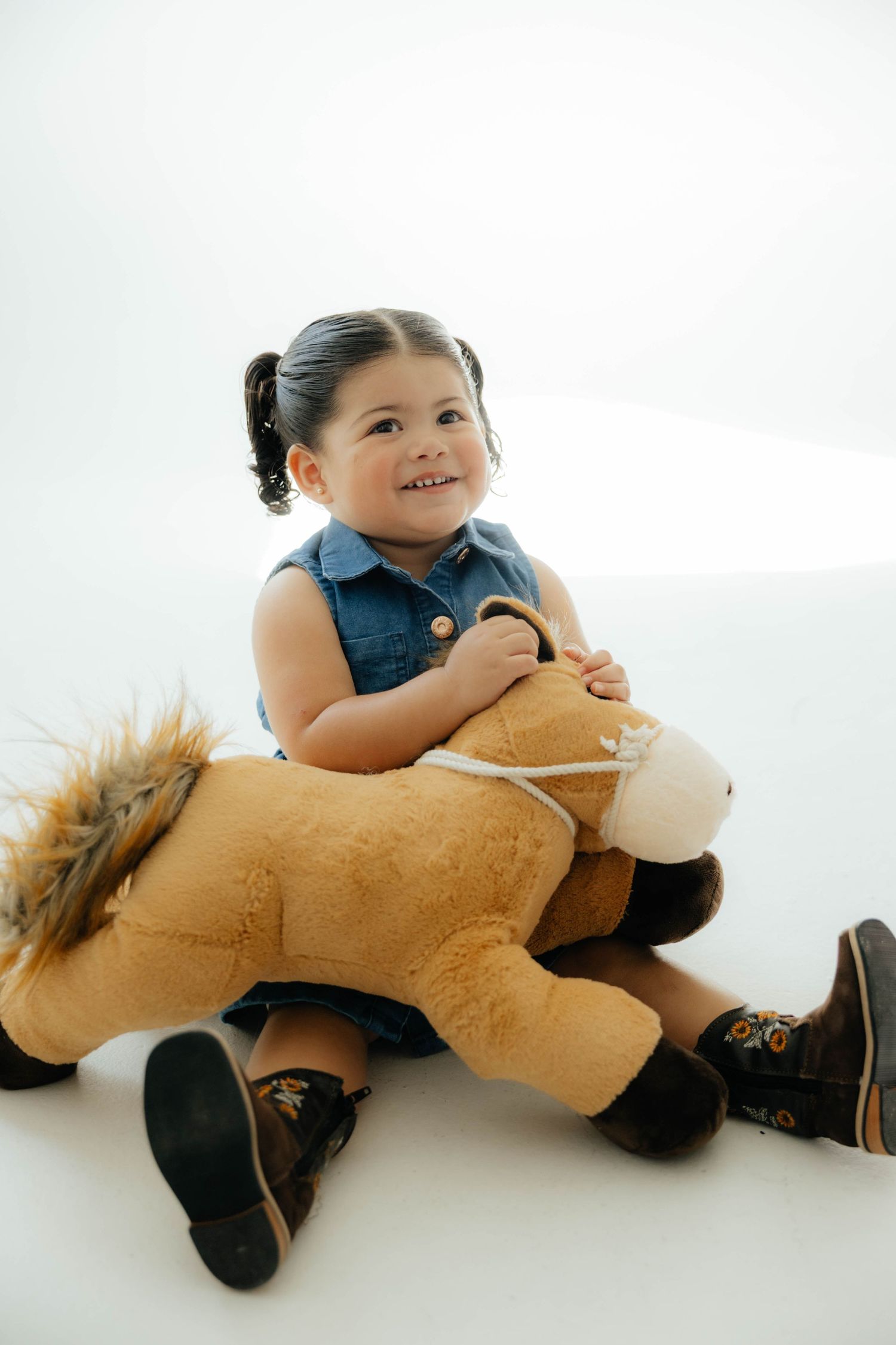 Small child cuddling with a large plush lion toy on white background.
